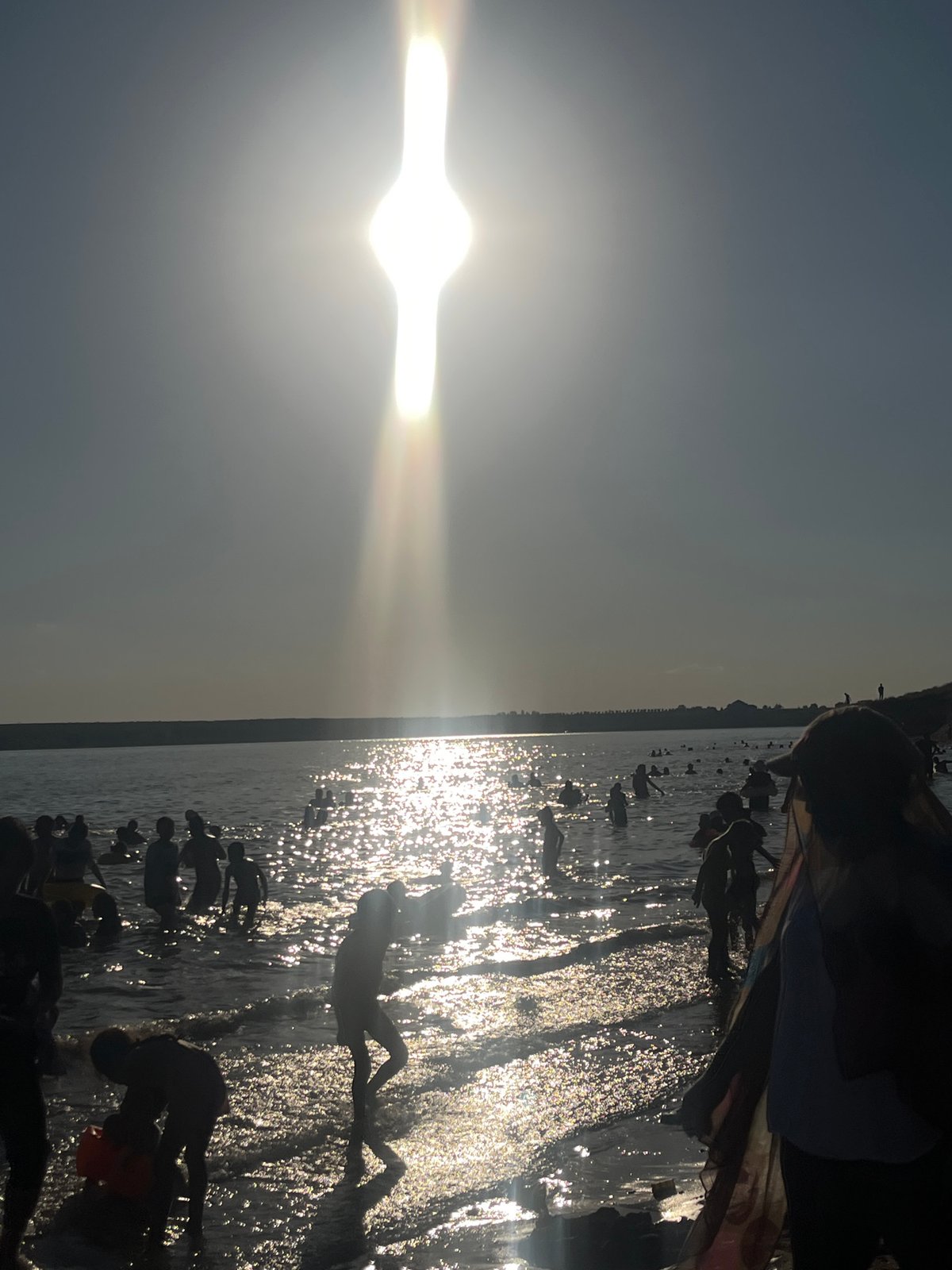 Crowded waterfront day: swimming, jet skis, and shoreline fun