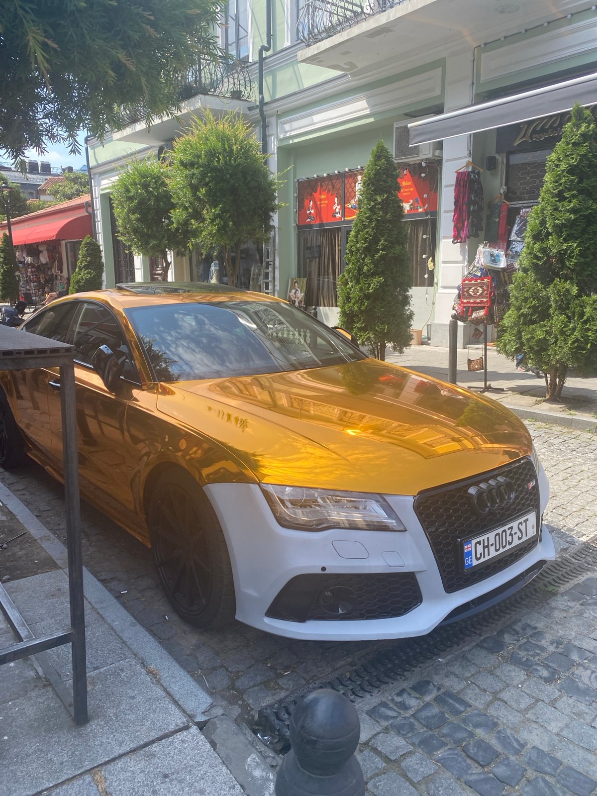 Gold Audi, blue taxi, and a stray dog on Batumi cobblestones