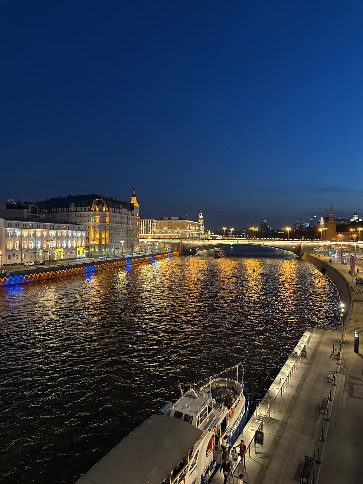 Evening cityscape observed along Moscow River featuring illuminated Stalinist architecture