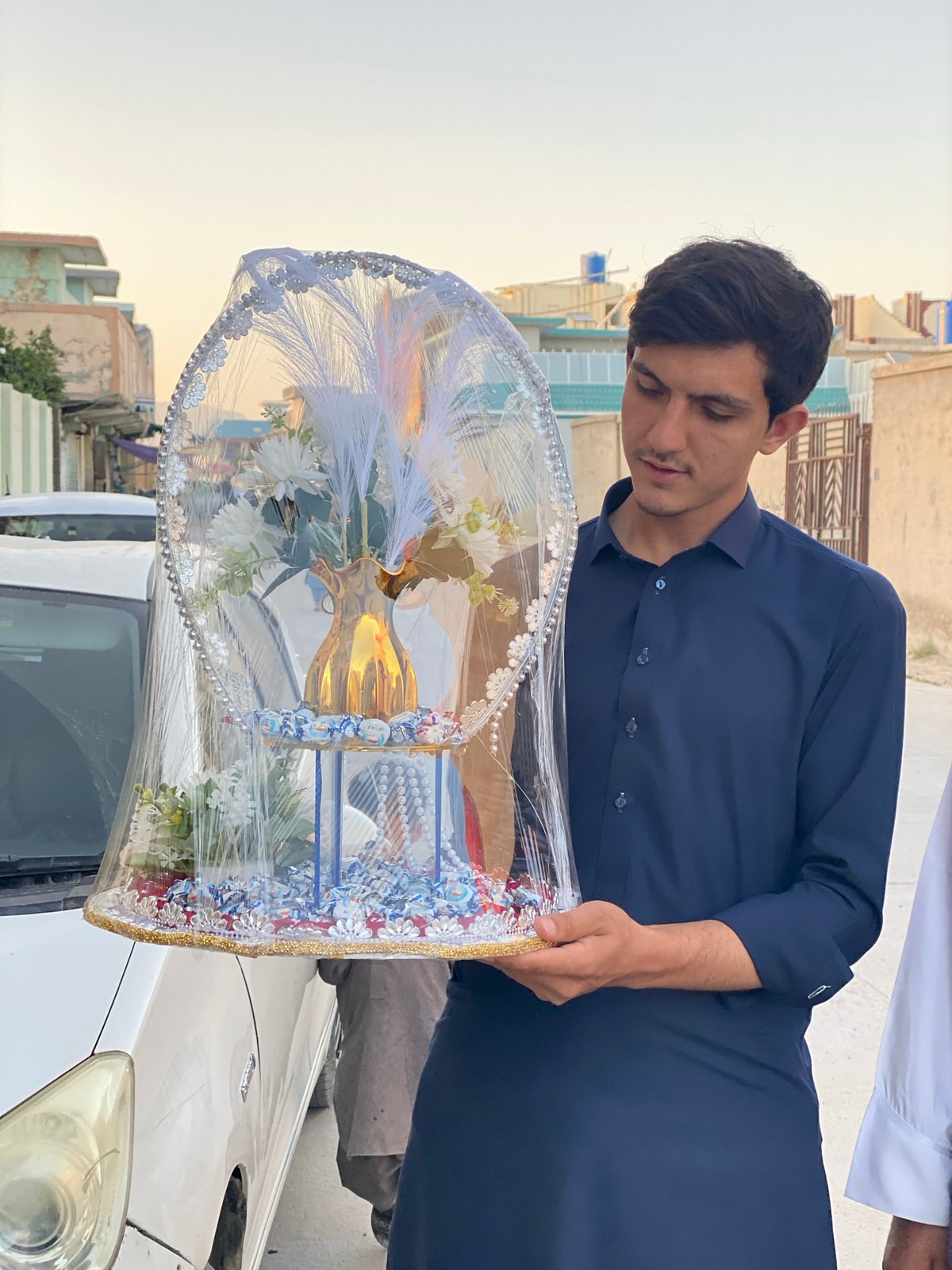 Man carries ornate gift basket on Kandahar street