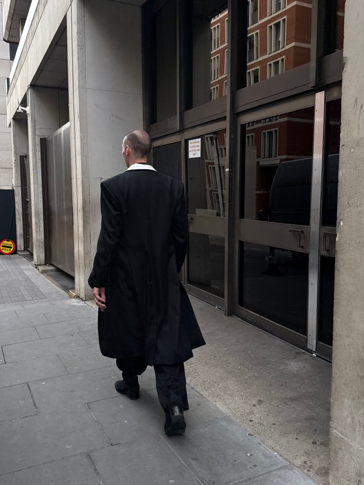 Man in black suit walks past London building