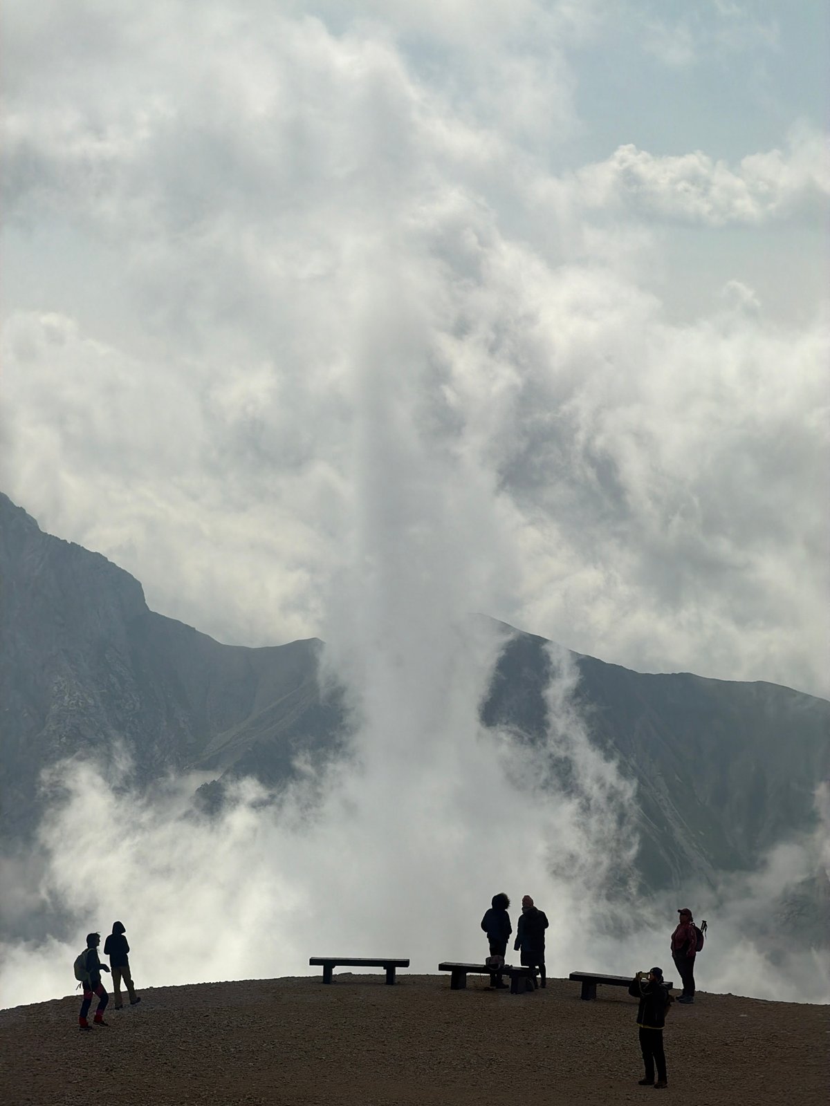 Hikers pause at a cloud-shrouded mountain overlook in Austria
