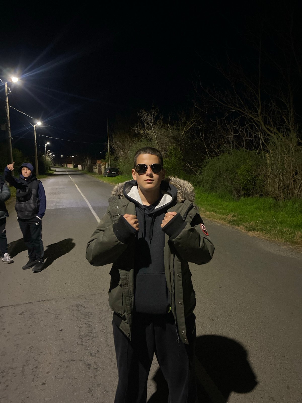 Teenagers gather on illuminated street in Goritsa, Bulgaria at night