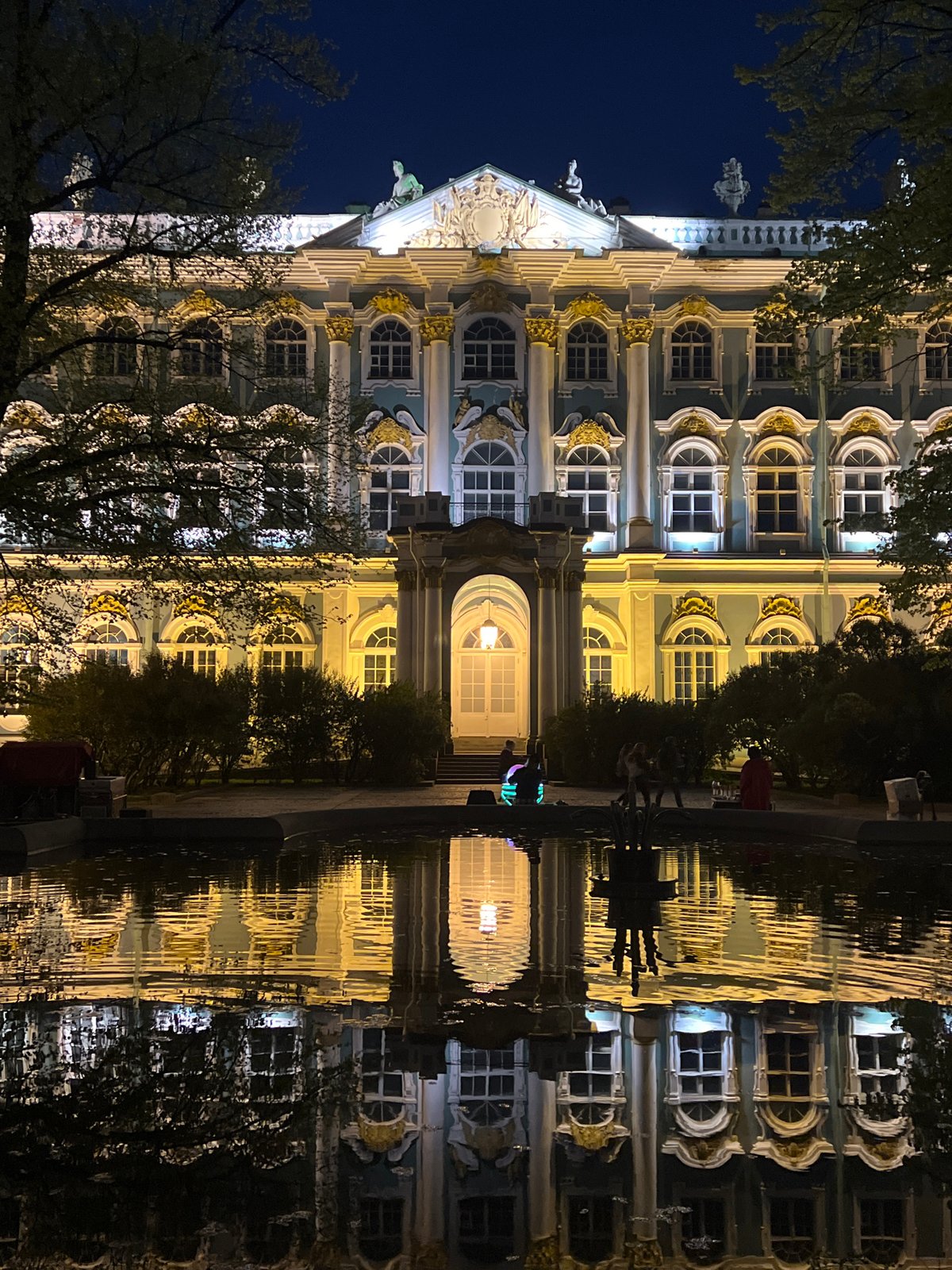 Night scenes around Winter Palace feature pedestrians, performer, Victory flags