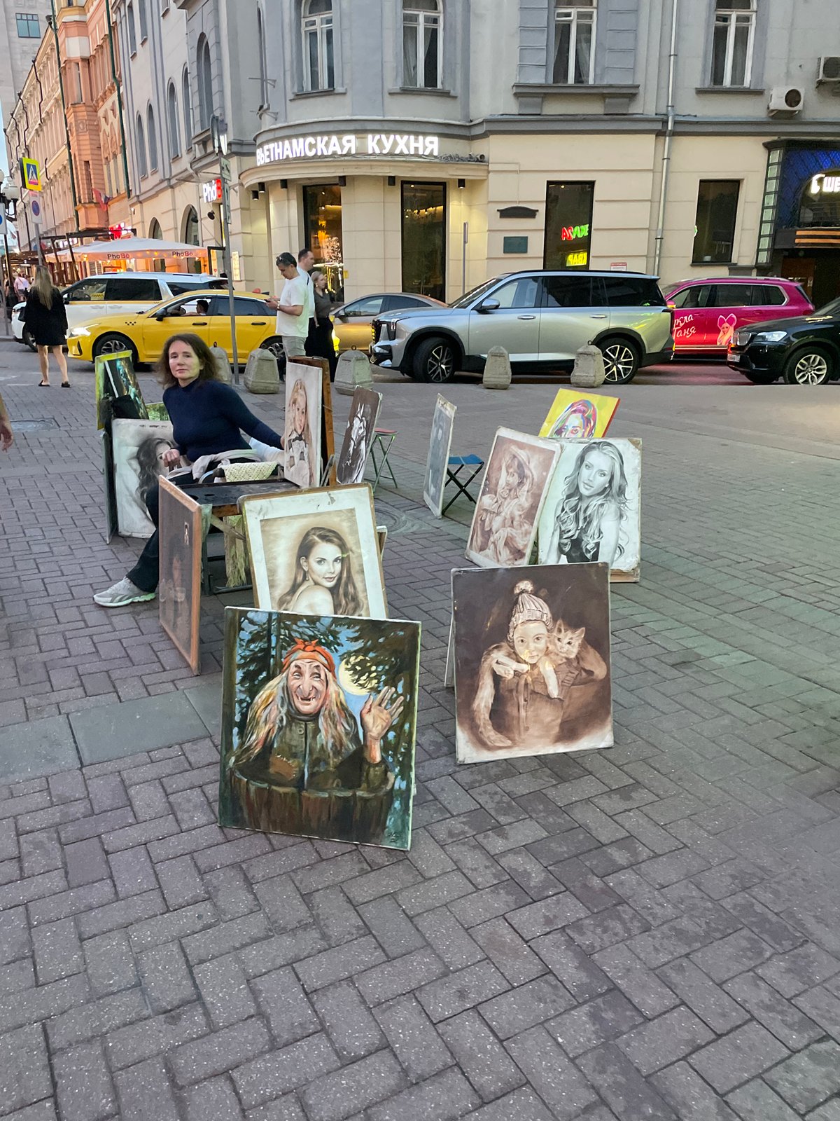 Street artists sell artwork on Moscow sidewalk near Vietnamese restaurant