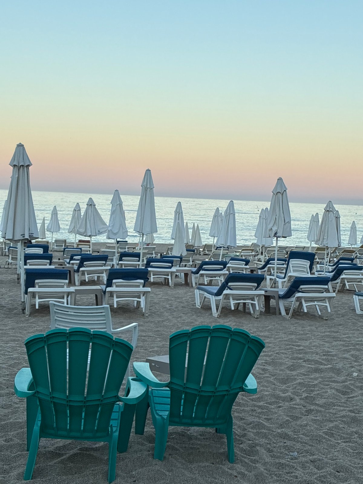 Alanya beach at golden hour, chairs, palms, and calm water