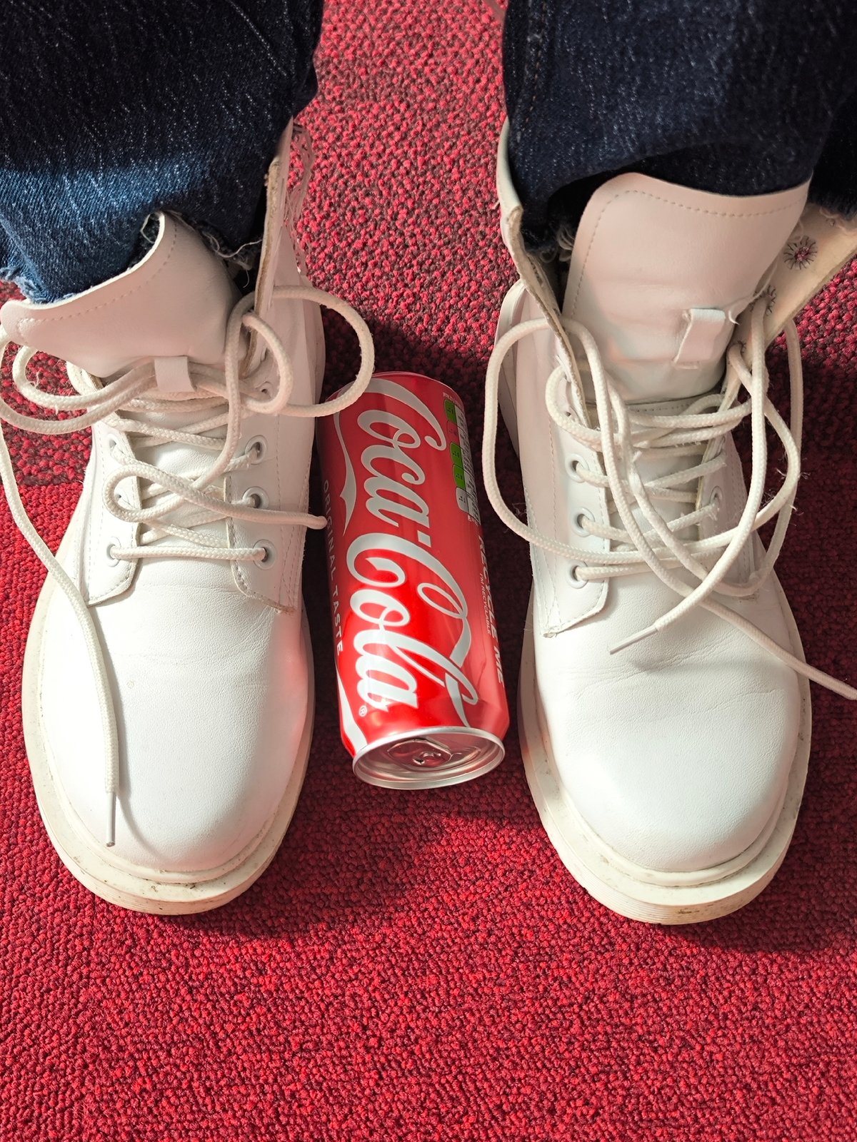 Person in white boots enjoys Coca-Cola on red carpet