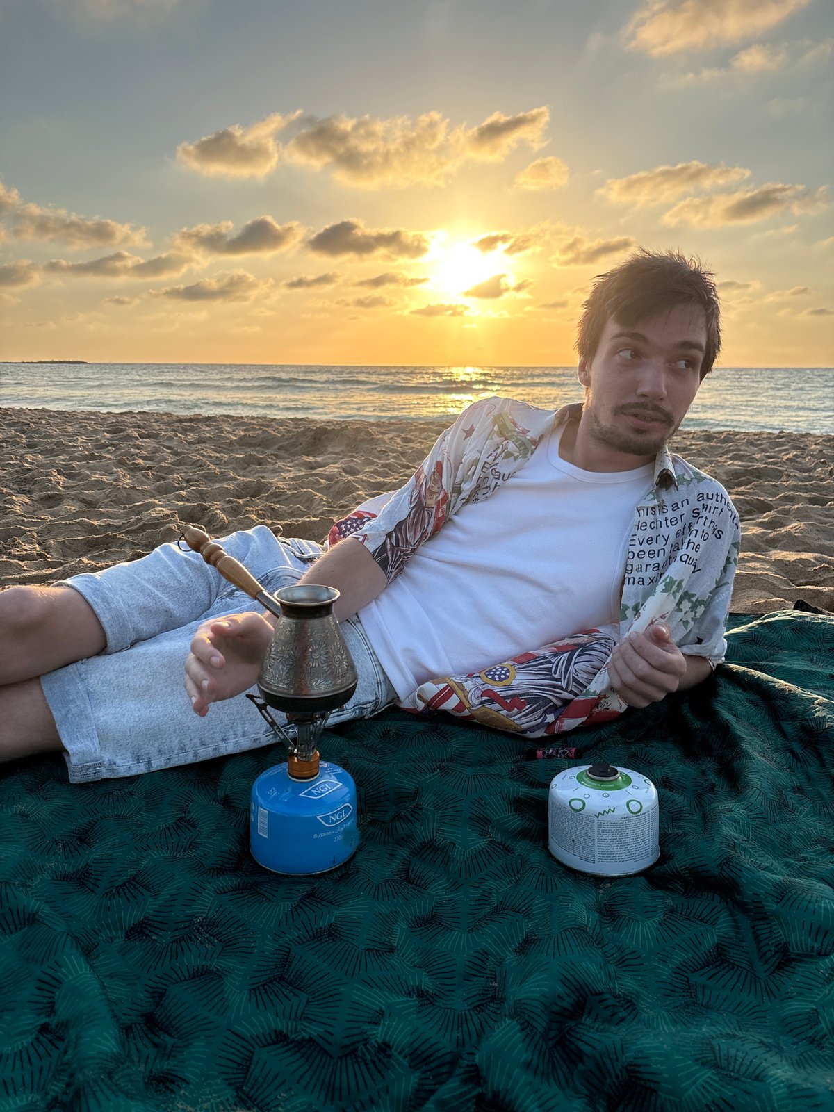 Beachgoer camps with portable stove at Israeli coast sunset