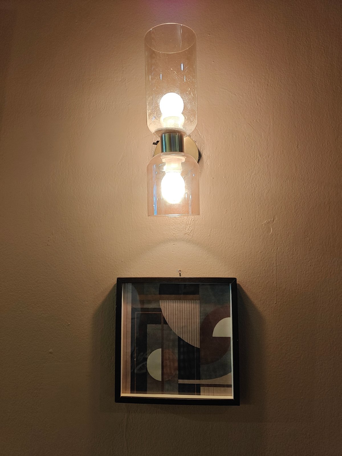 Modern dual-cylinder light fixture observed above artwork in Mumbai