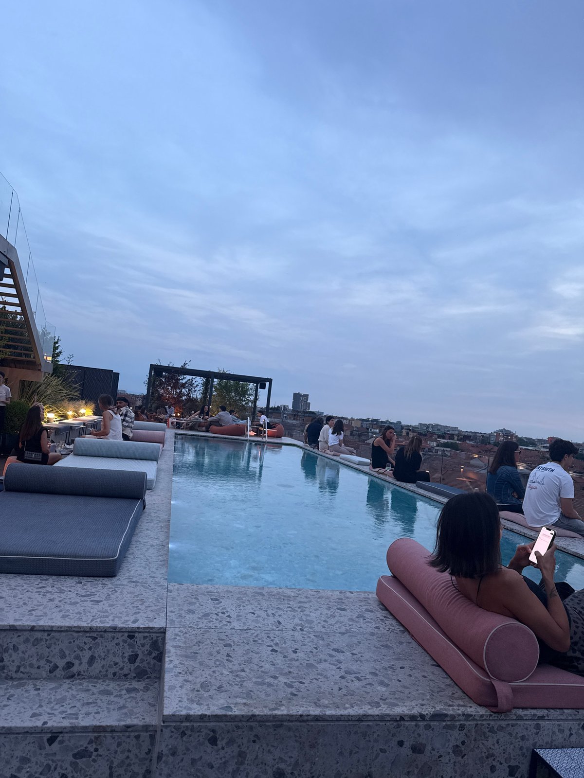 Evening rooftop pool party documented across Milan skyline