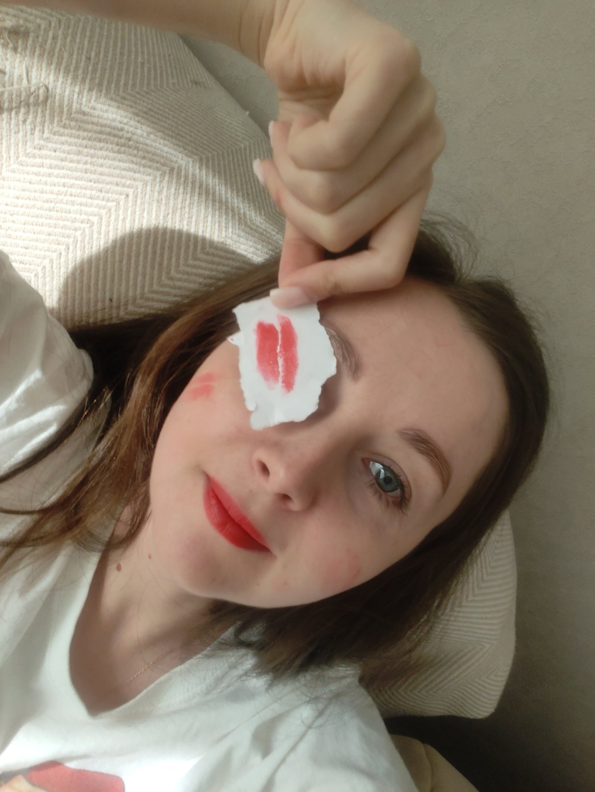 Woman plays with lipstick-marked papers indoors