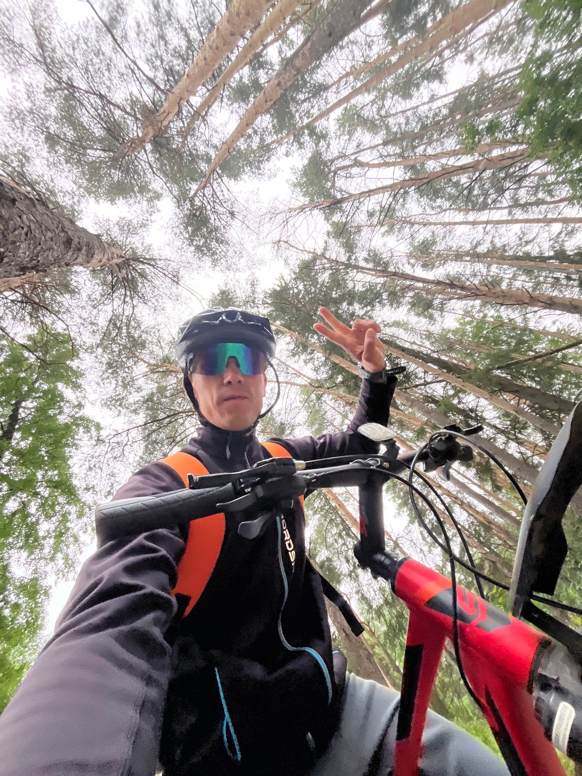 Cyclist pauses beneath forest canopy in Chaikovsky, Russia