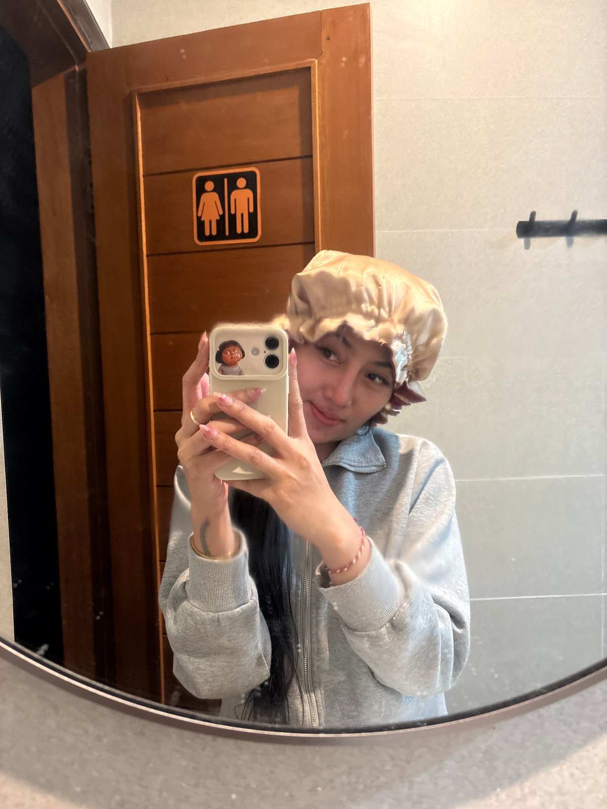 Person takes mirror selfie wearing bonnet and casual attire