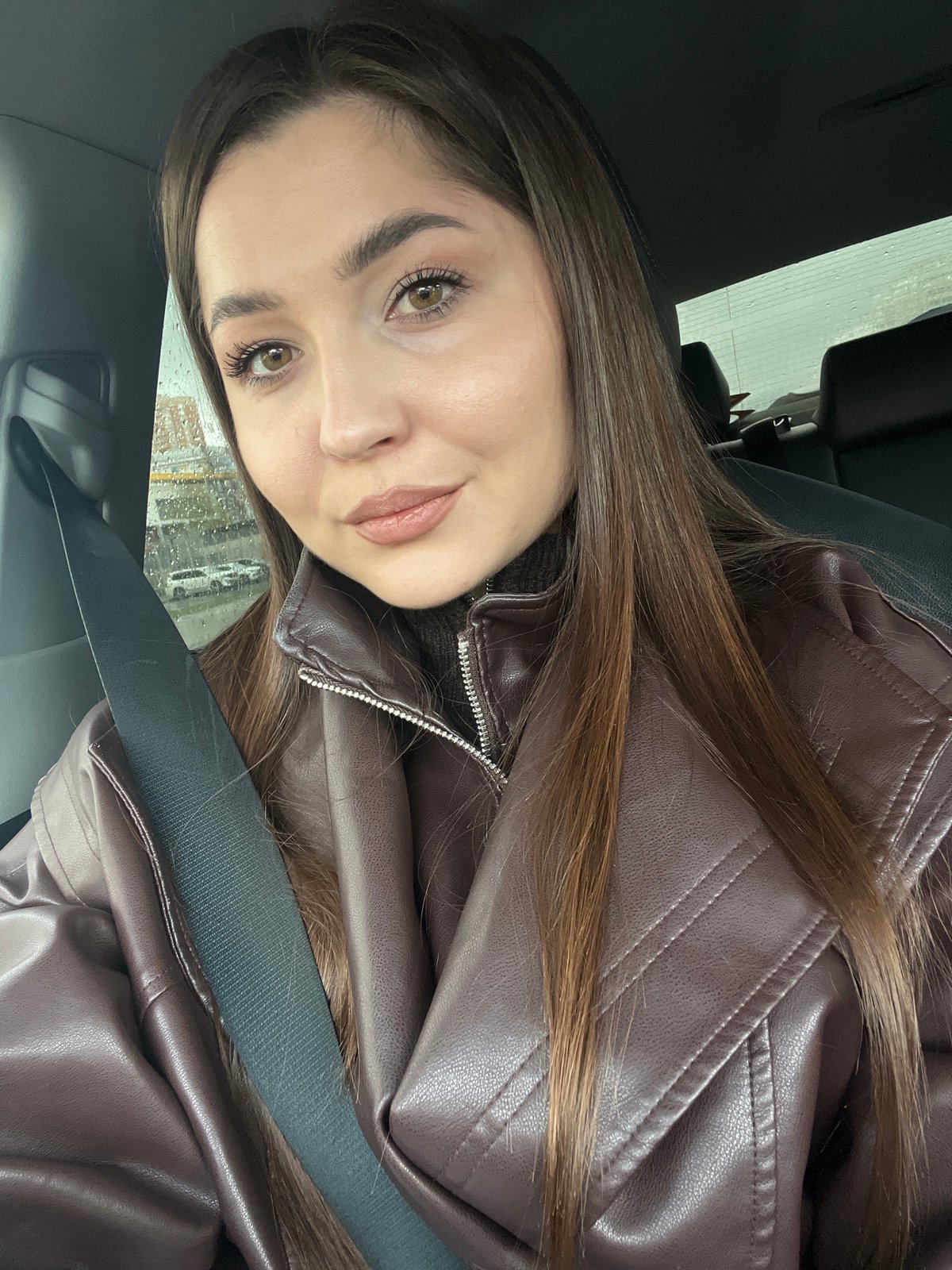 Woman drinks coffee while driving through rainy Moscow morning traffic