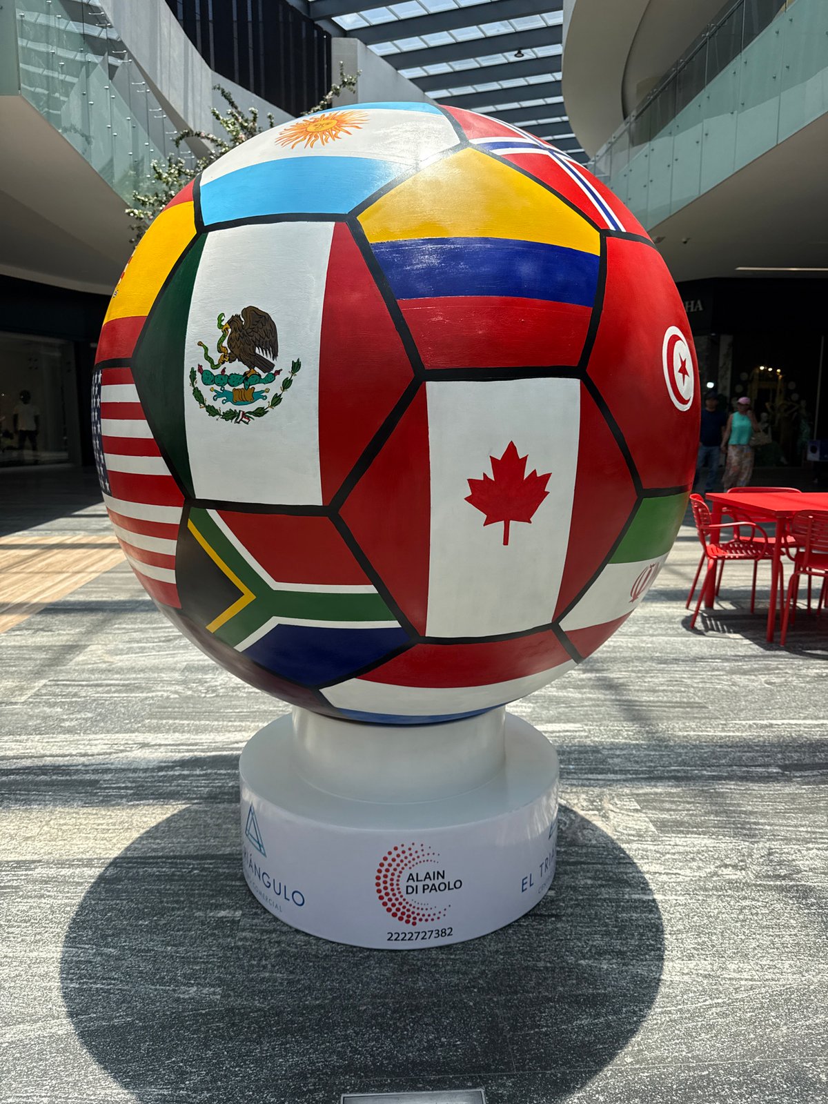 Flag-decorated soccer ball sculpture displayed in Puebla commercial space