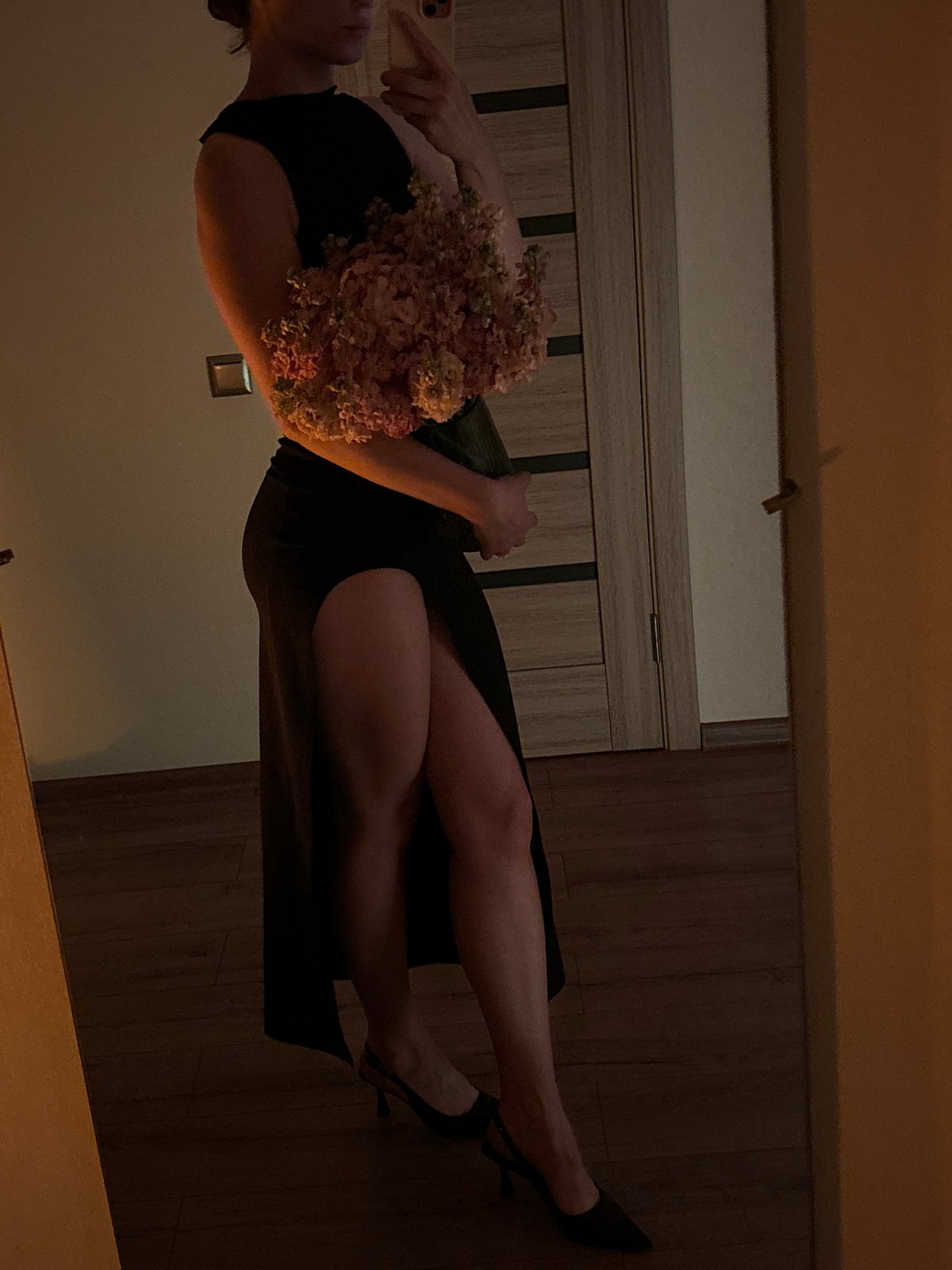 Pink and white flower bouquet held indoors against a black outfit