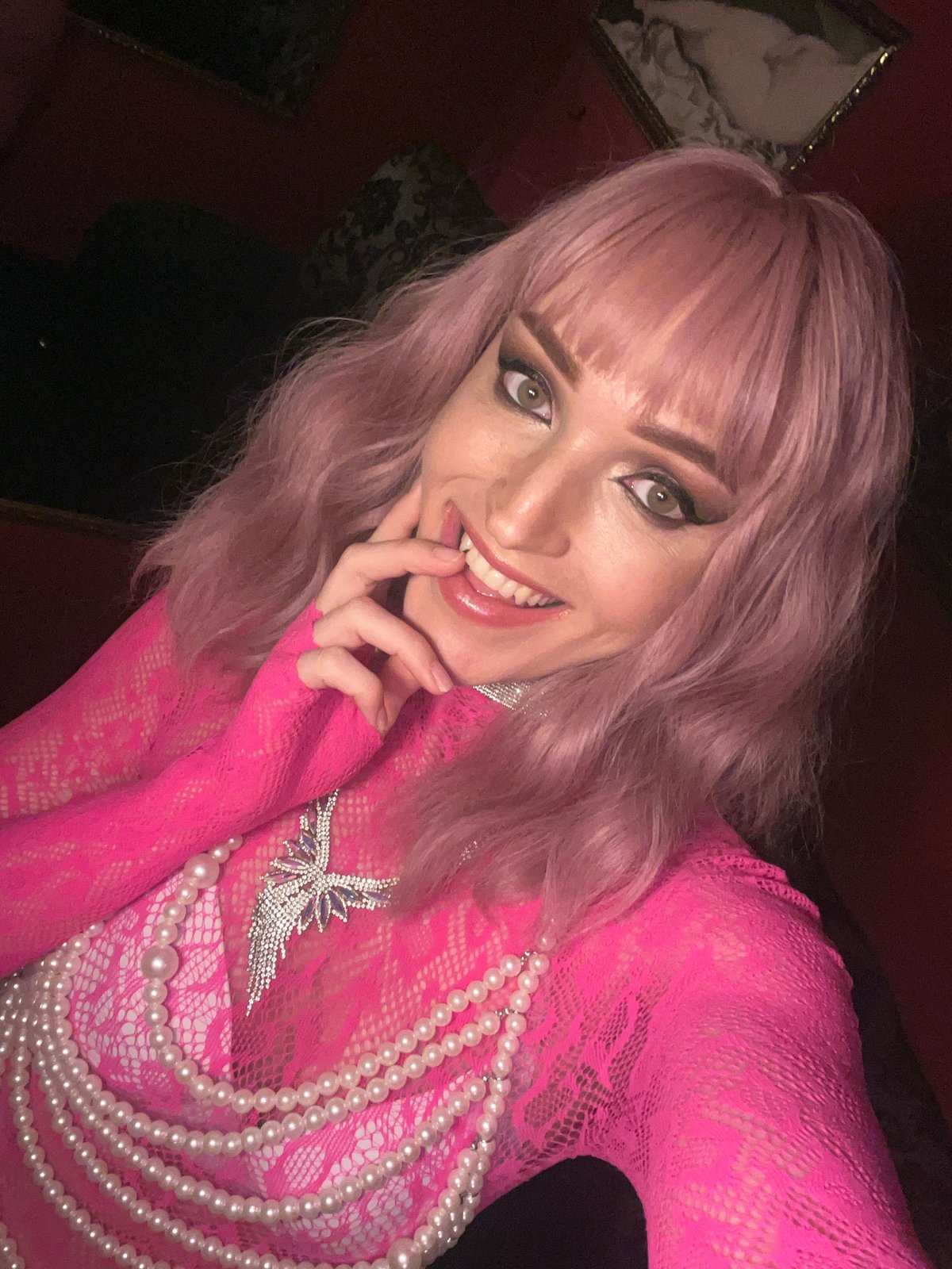 Pink-haired person photographed in selfies wearing bright pink outfit