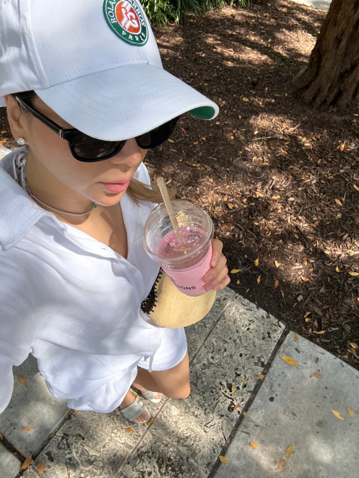 Person in white photographed with drink on Miami Beach