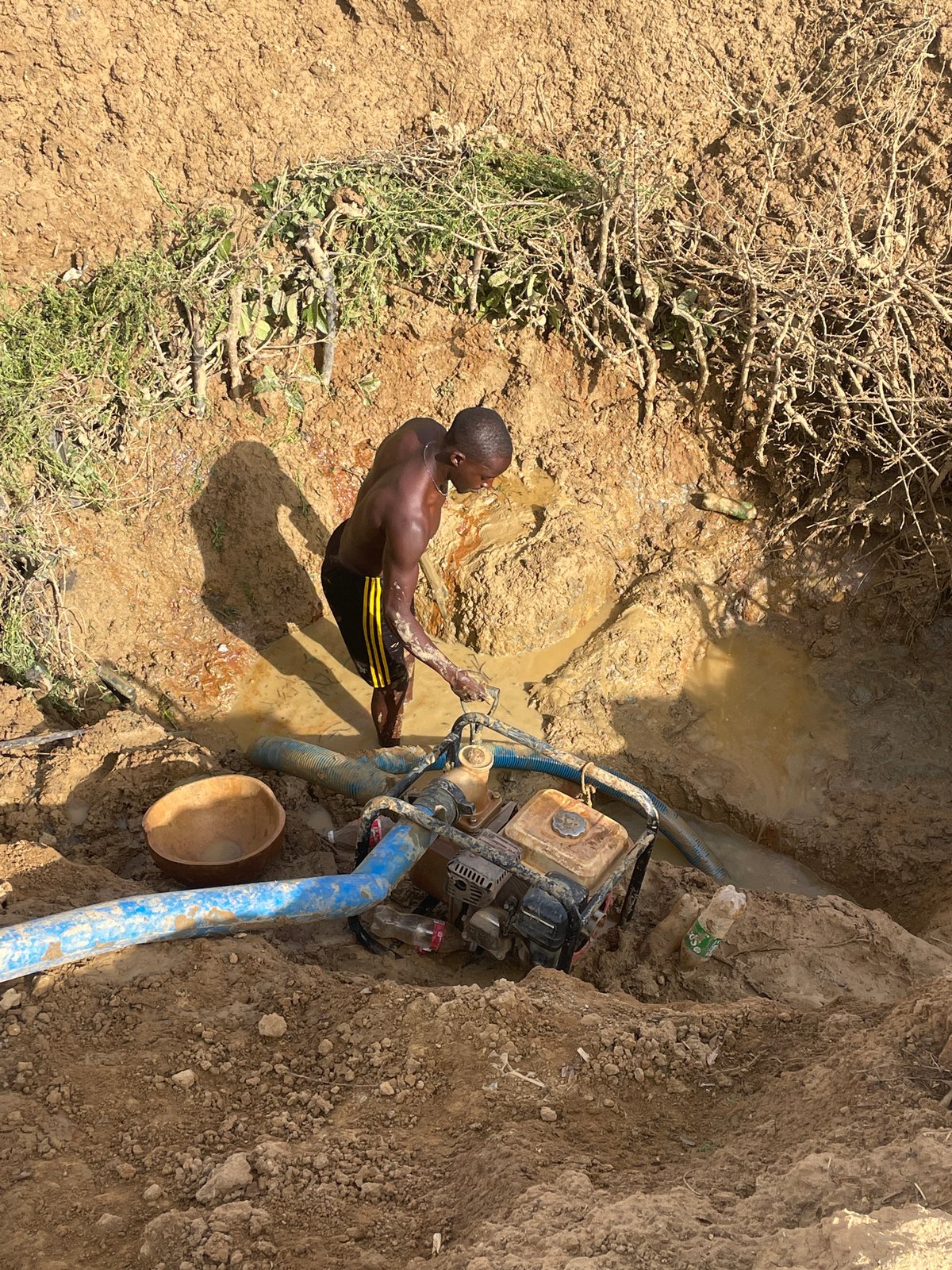 Man works at muddy water pit in Gana Daji