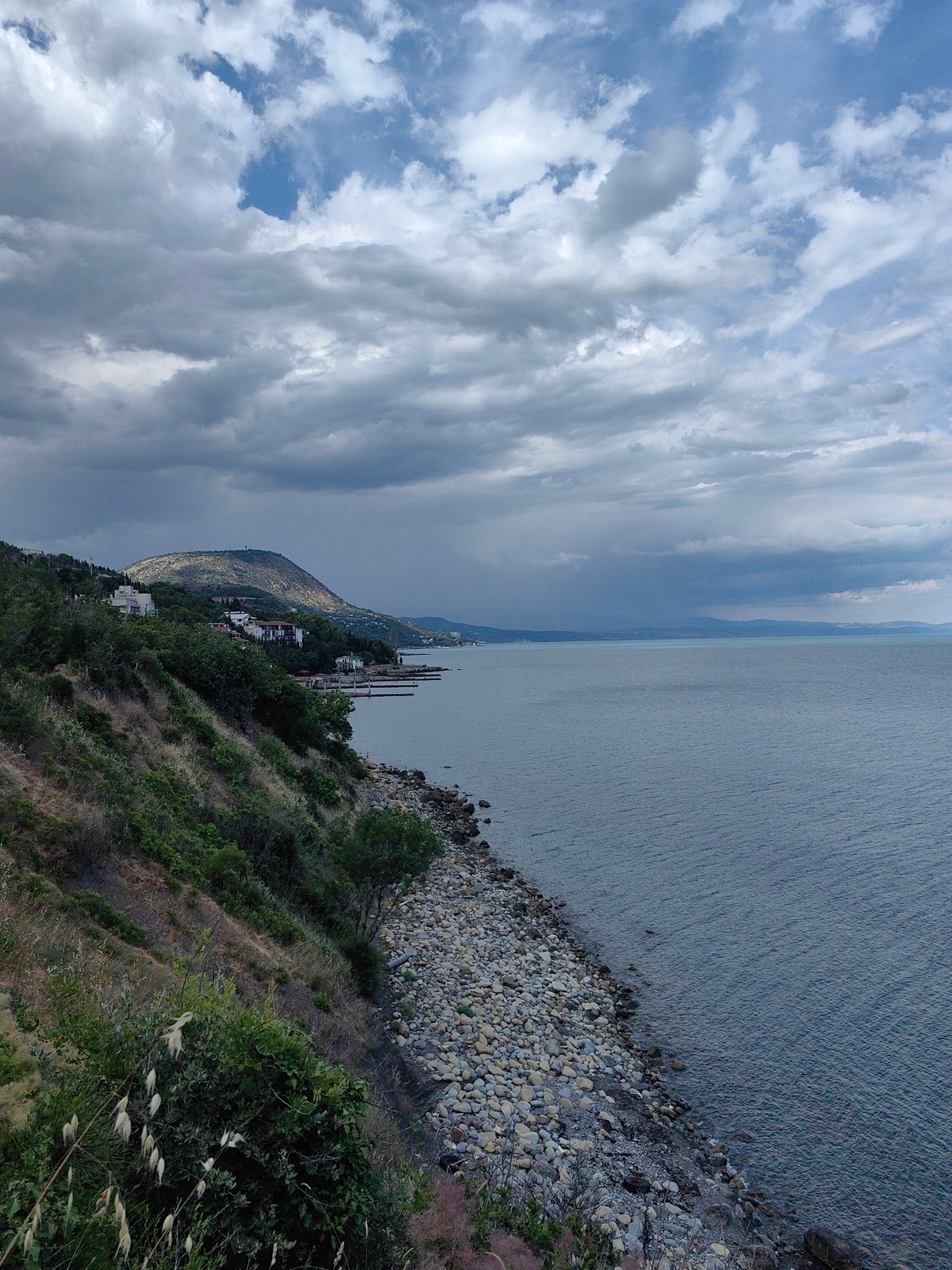 Rocky Crimean coastline with hillside buildings under overcast skies