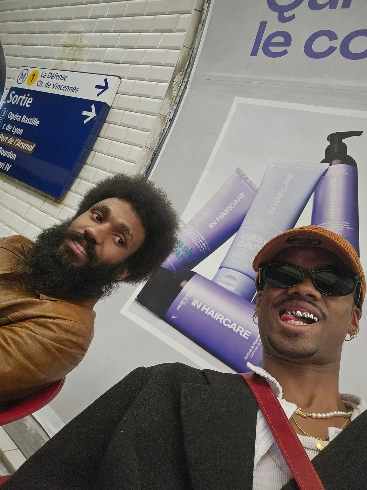 Two men pose for photos in Paris Metro station