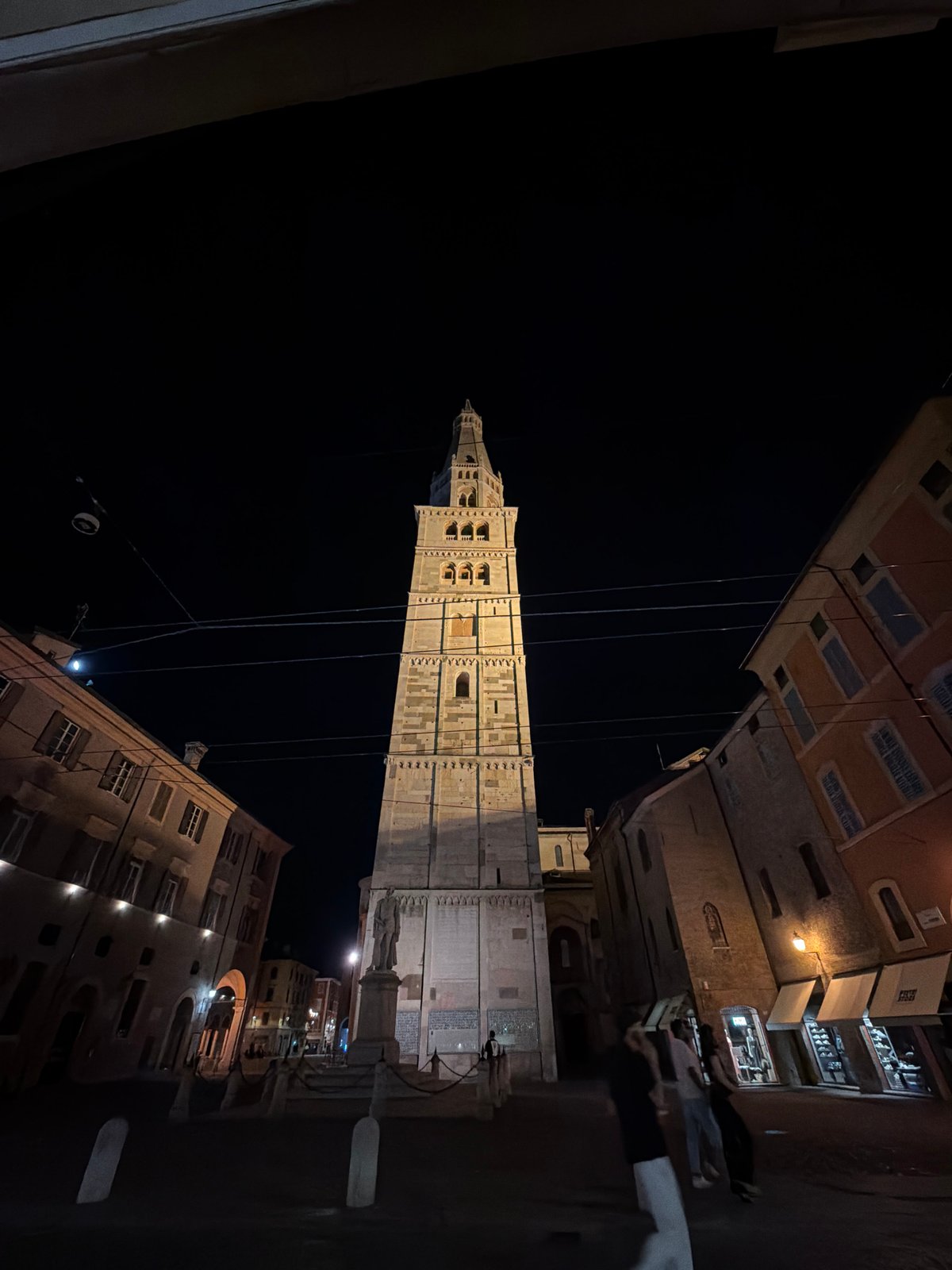 Modena's illuminated towers and umbrella-lined streets at night