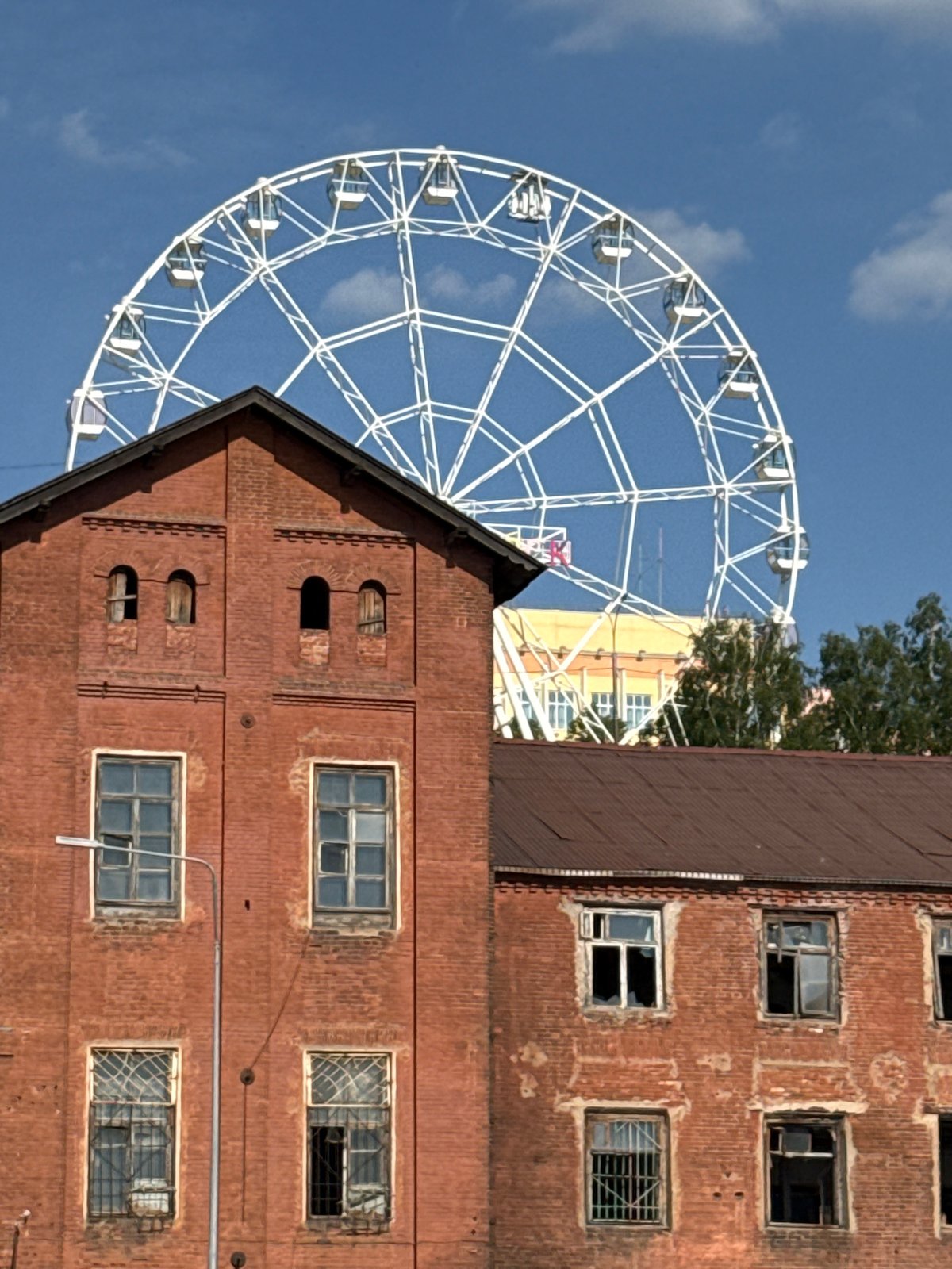 White Ferris wheel spotted against blue sky in Izhevsk