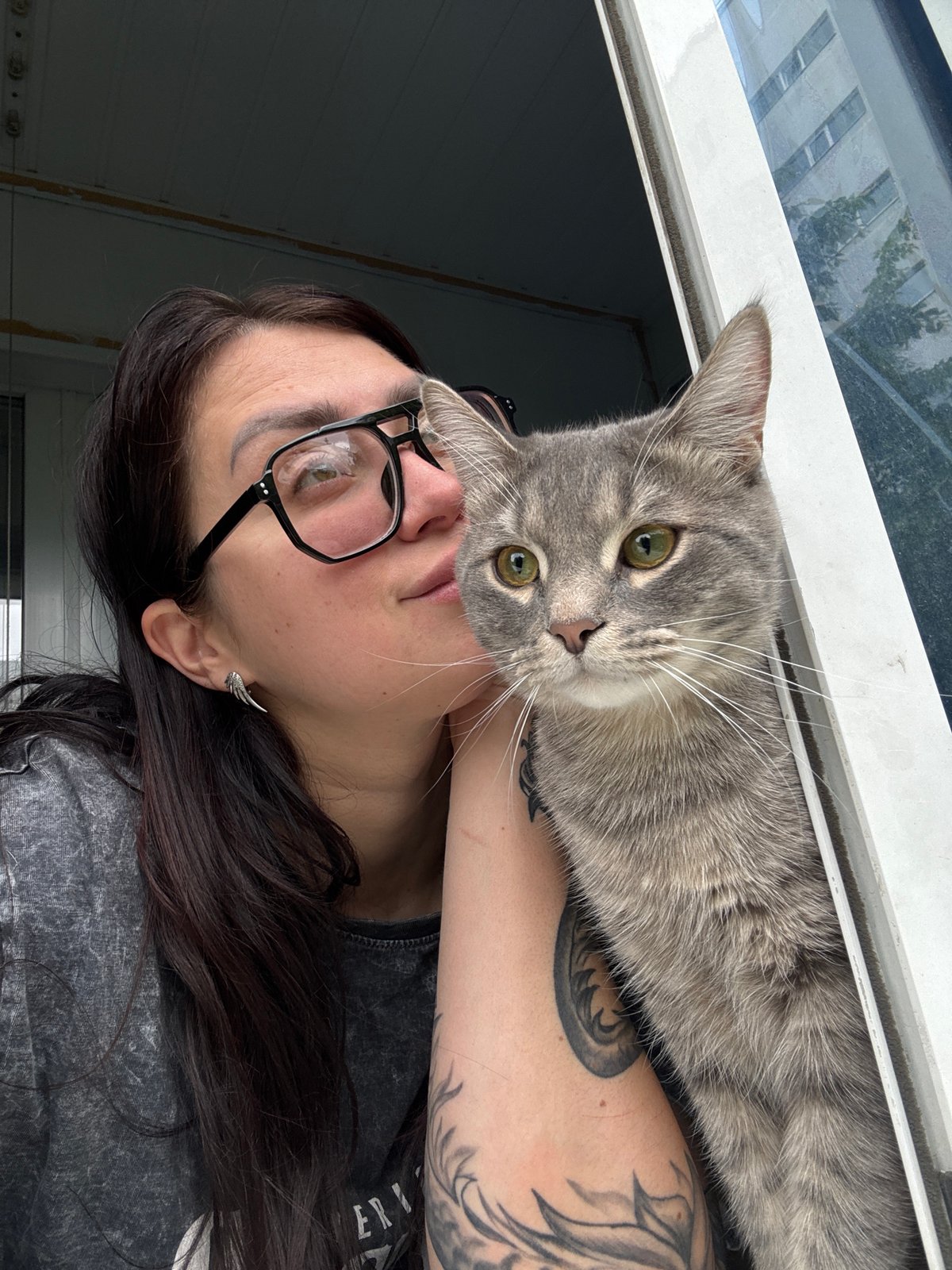 Woman with glasses and cats share morning window moments