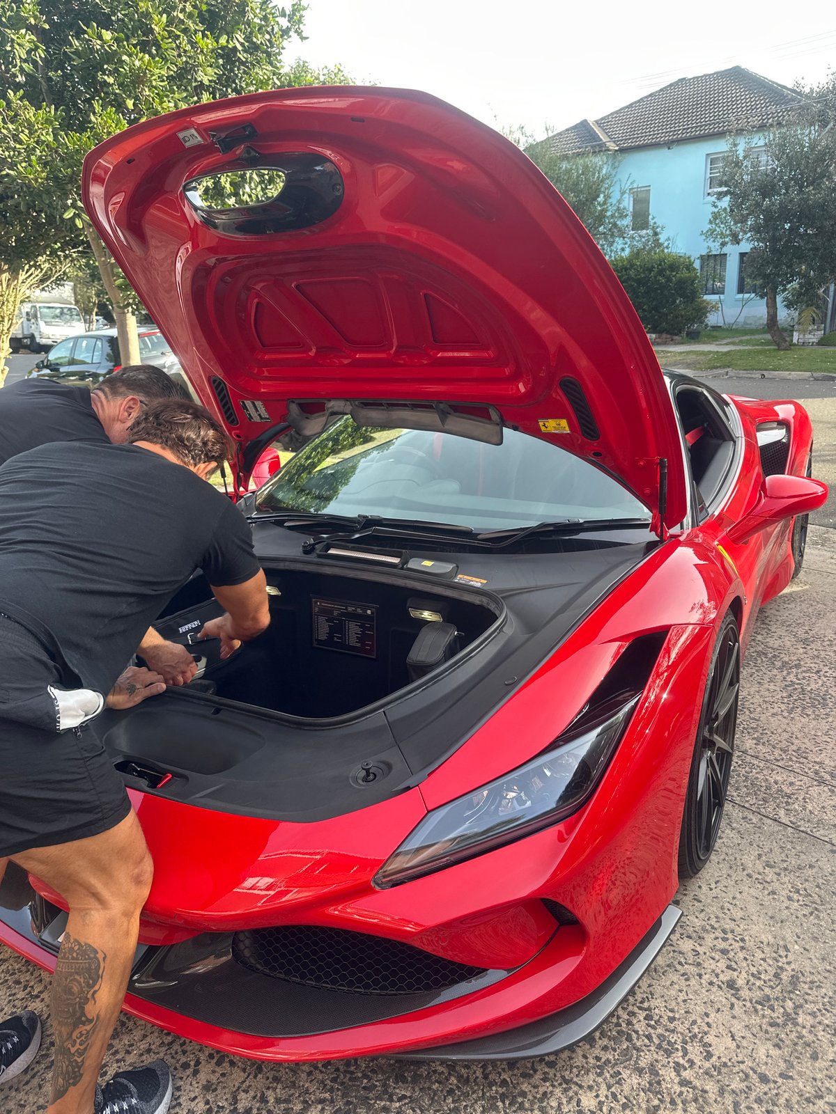 Two men service red Ferrari's front trunk in Maroubra