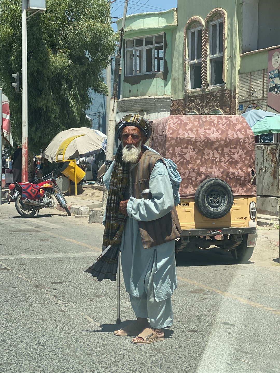 Elderly man in traditional dress stands on Kandahar street