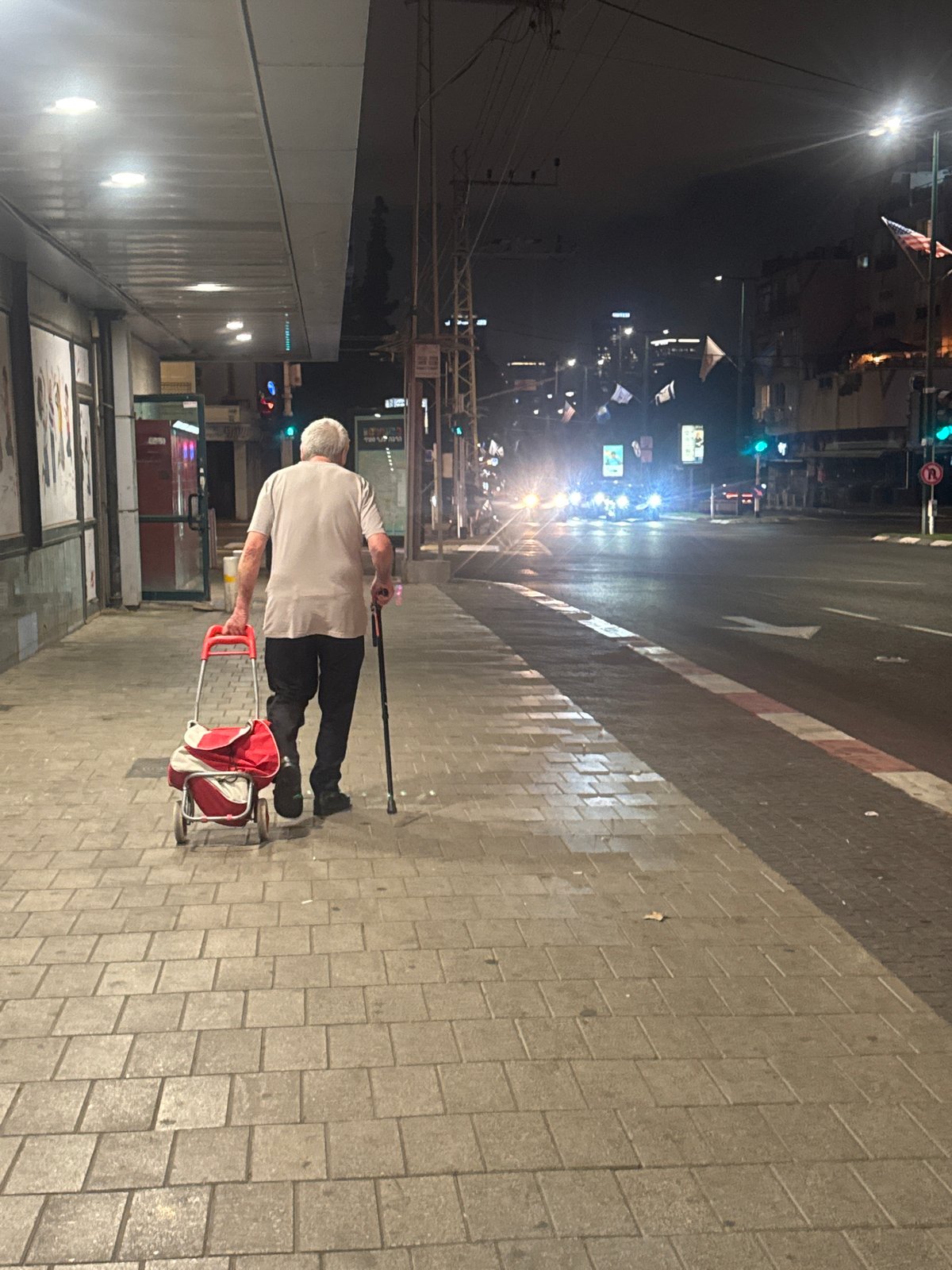 Elderly man shops along illuminated Israeli streets at night