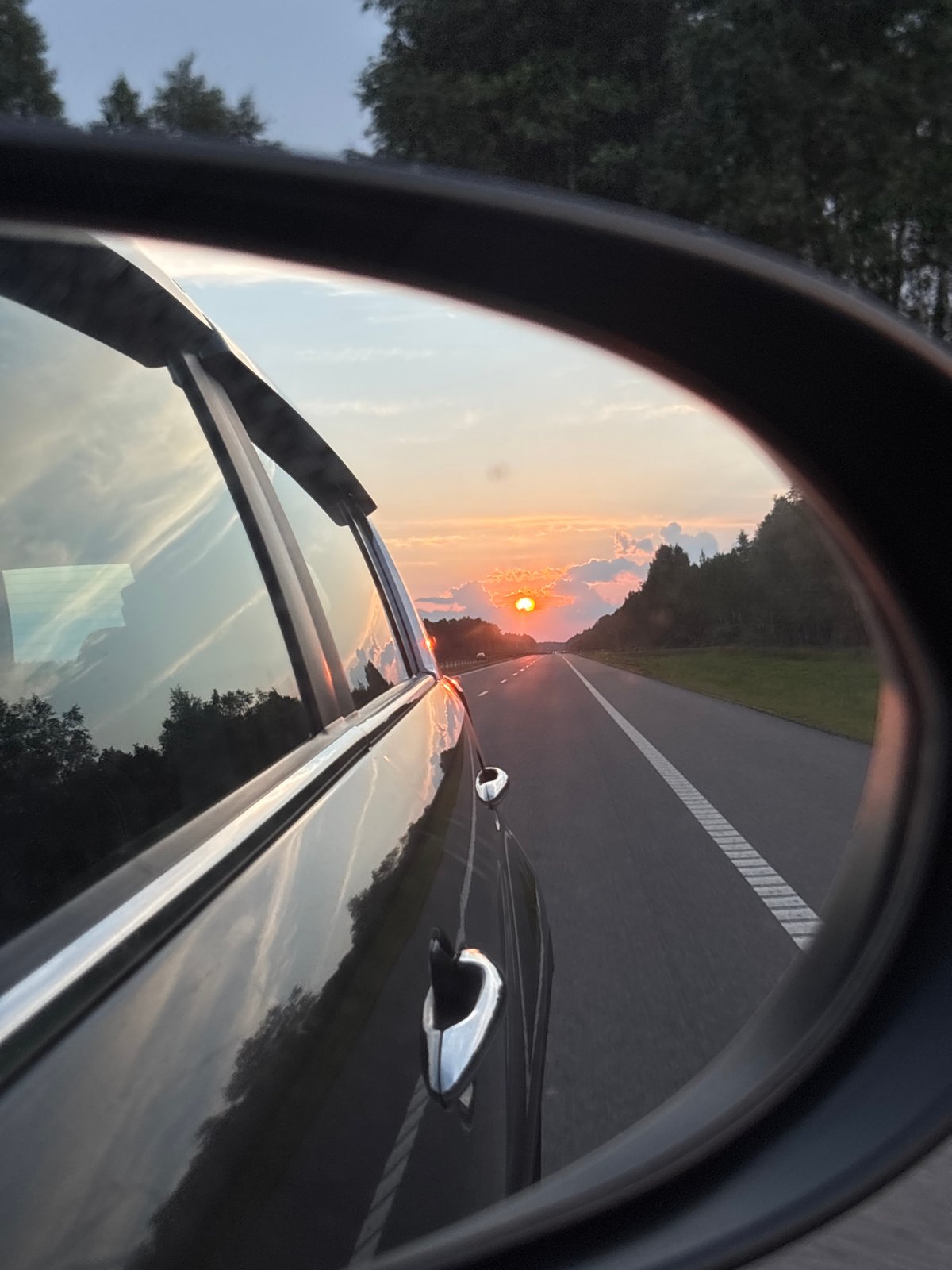 Sunset reflected in a rearview mirror on a Belarus highway