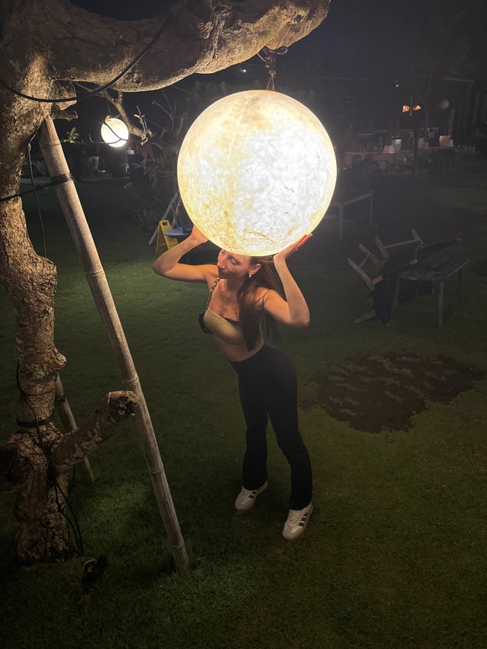 Woman interacts with illuminated sphere lamp in Indonesian city
