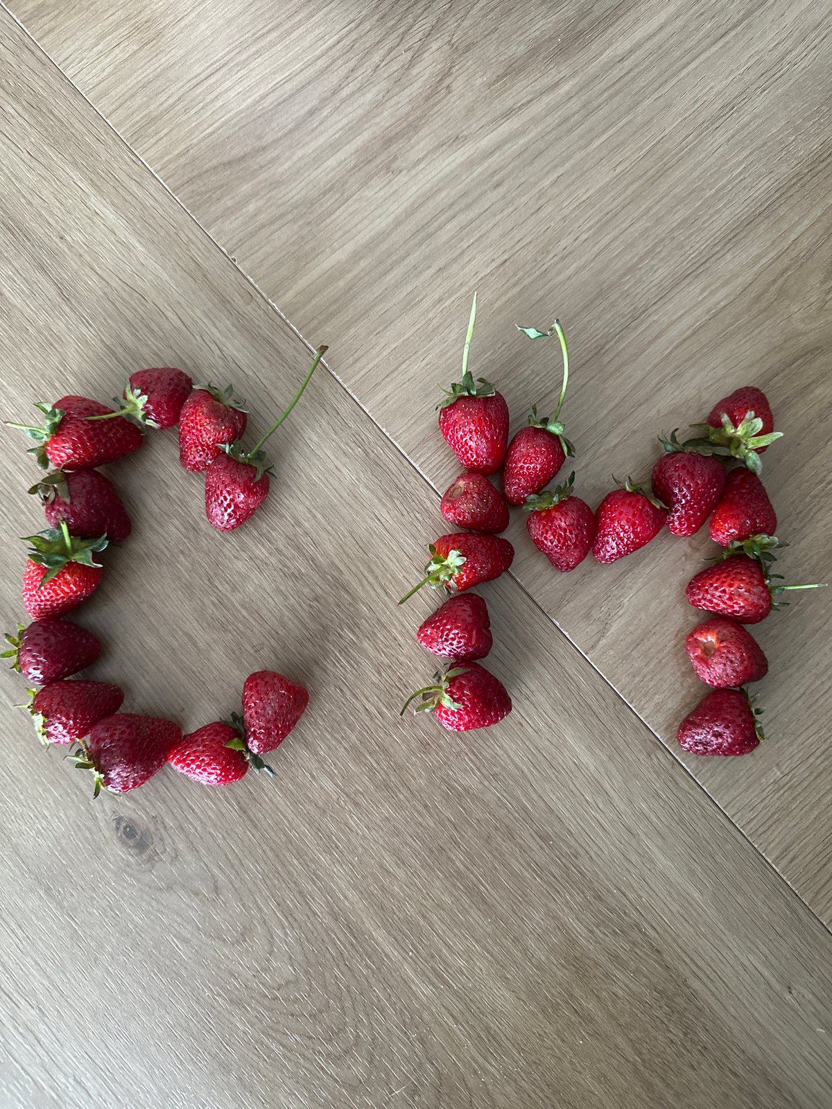 Berry art arrangement spells out messages on wooden floor