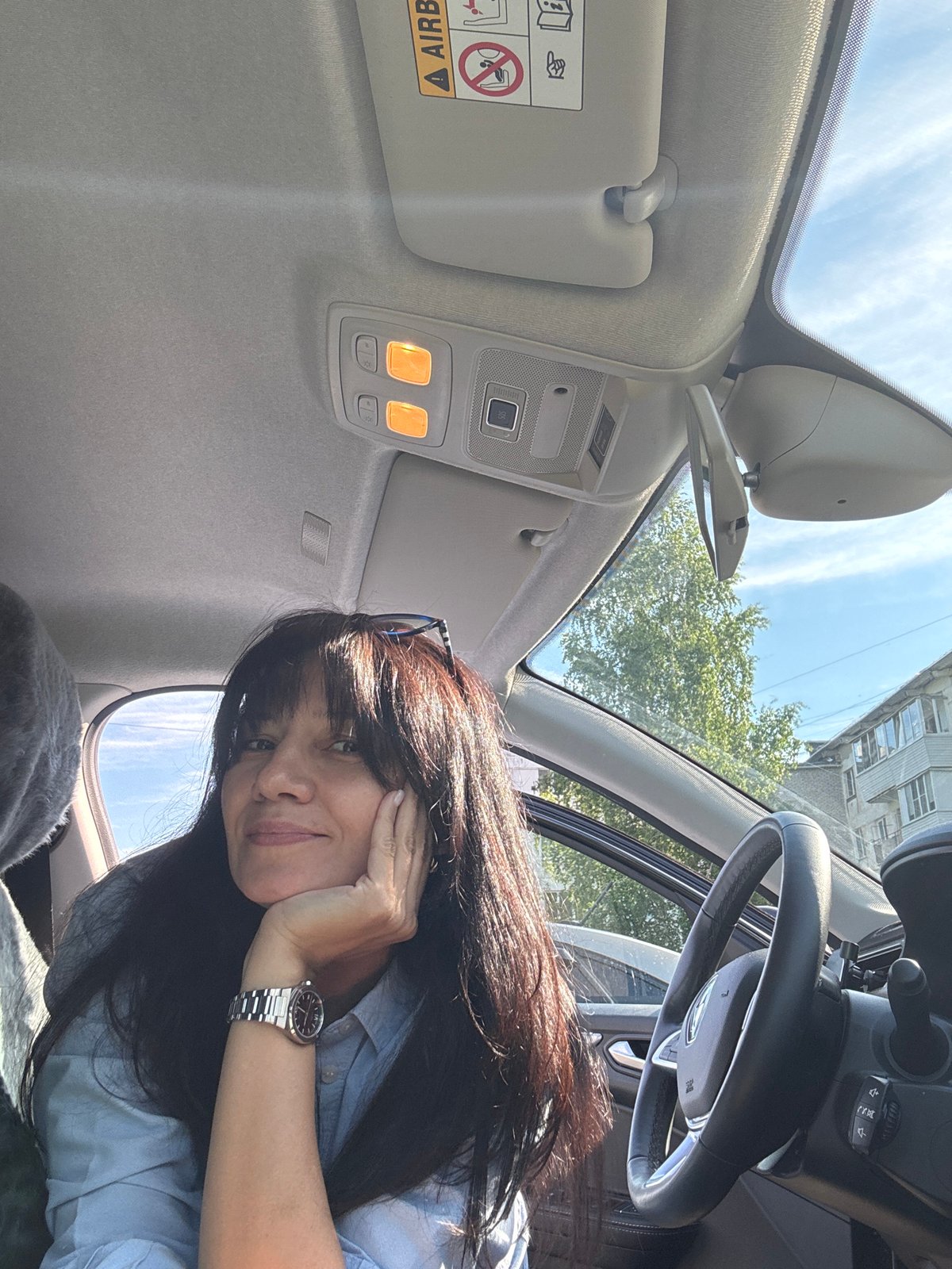 Woman photographed smiling in car during sunny day in Chaikovsky