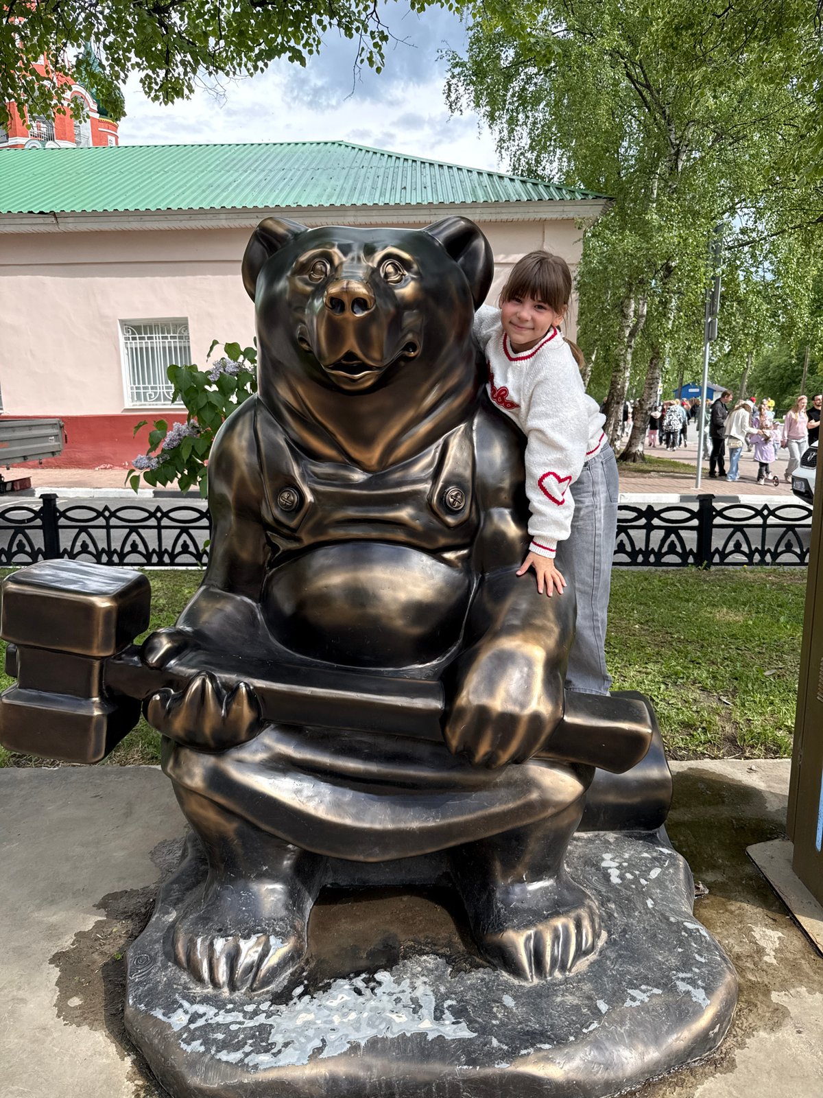 Visitors pose with bronze bear statue in Rusanovo