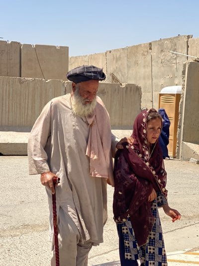 Elderly man walks with young woman's assistance in Kandahar