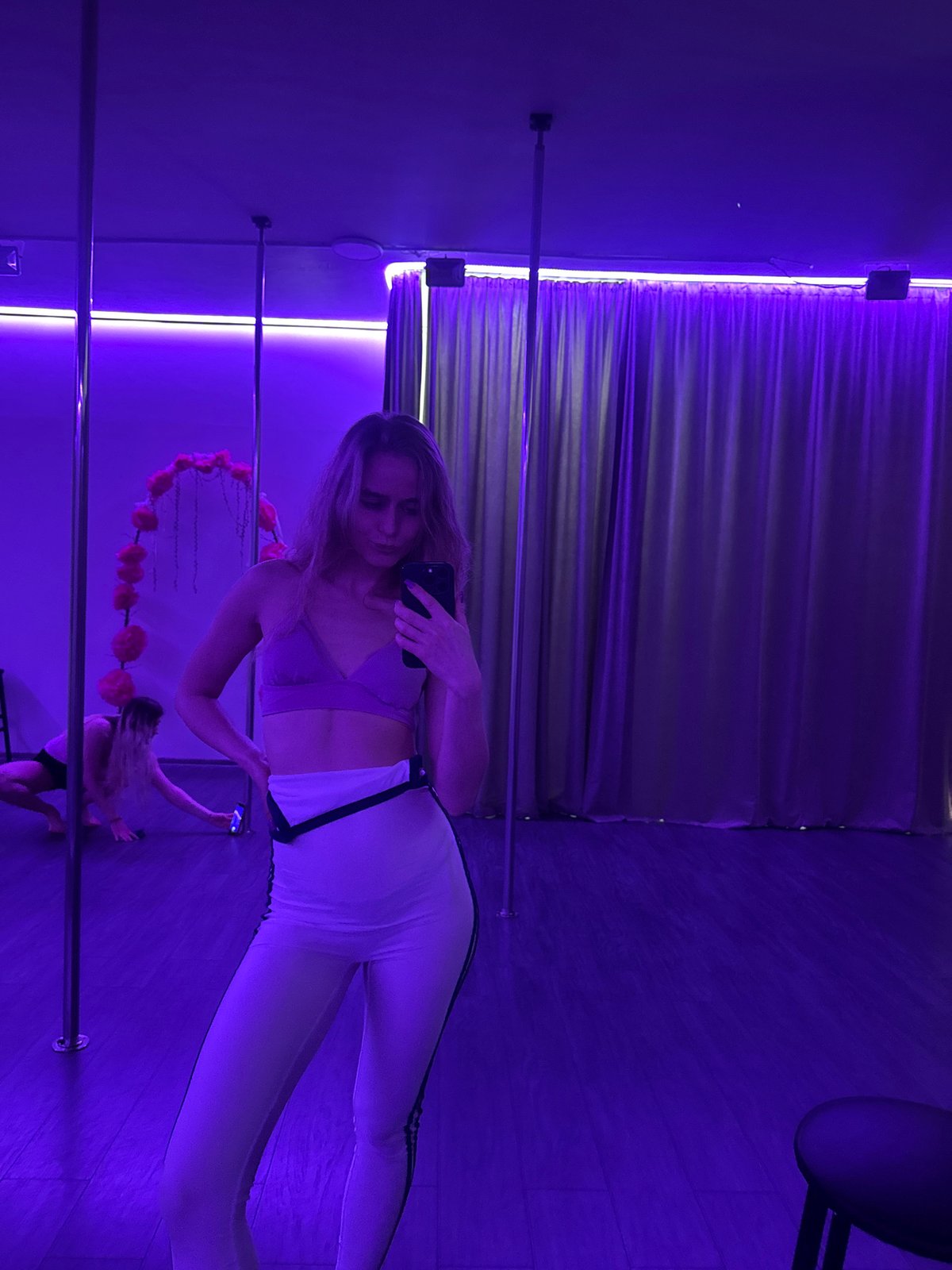 Pole fitness class documented at purple-lit studio