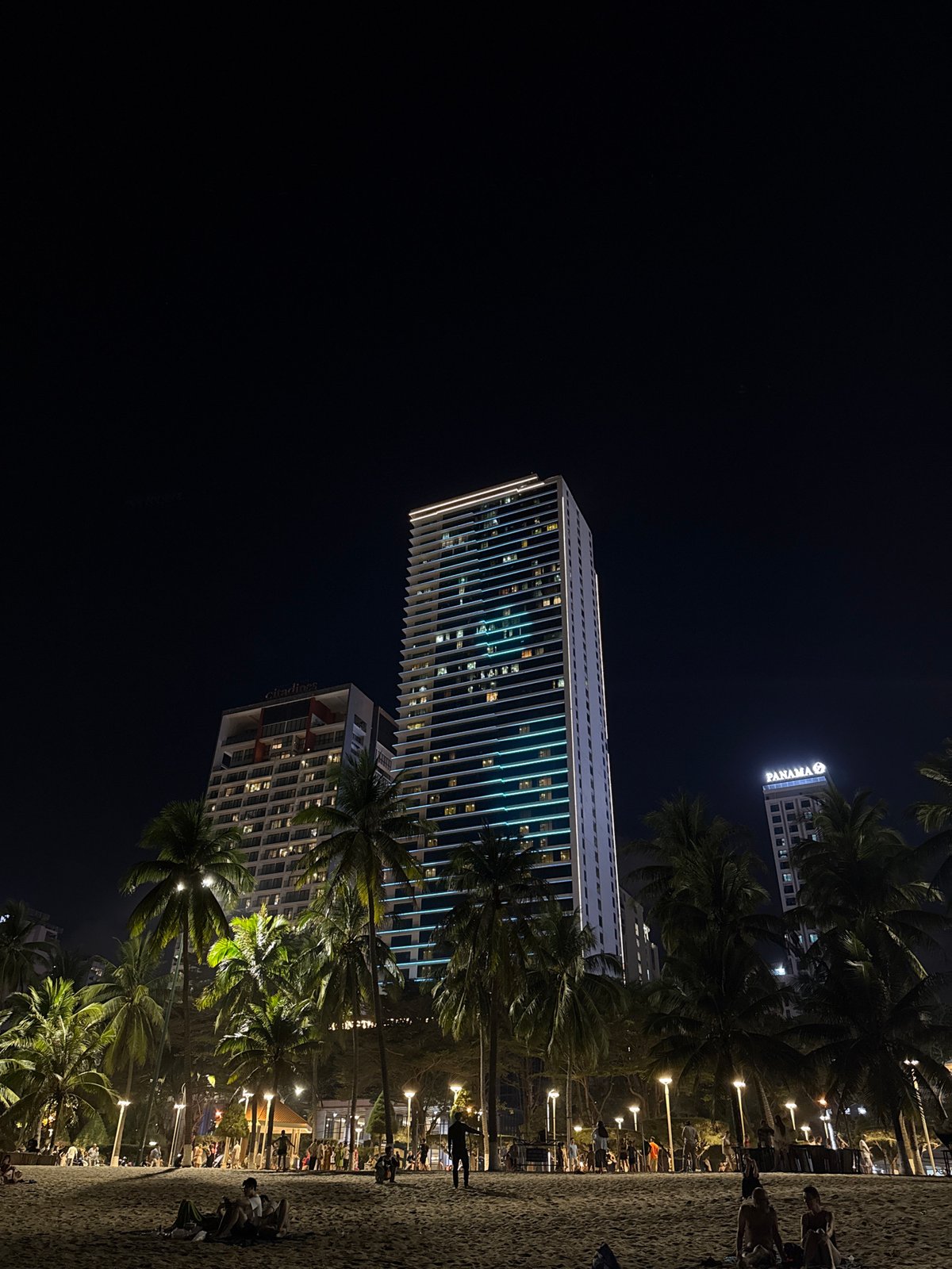 Street musician performs near Nha Trang skyscrapers under full moon