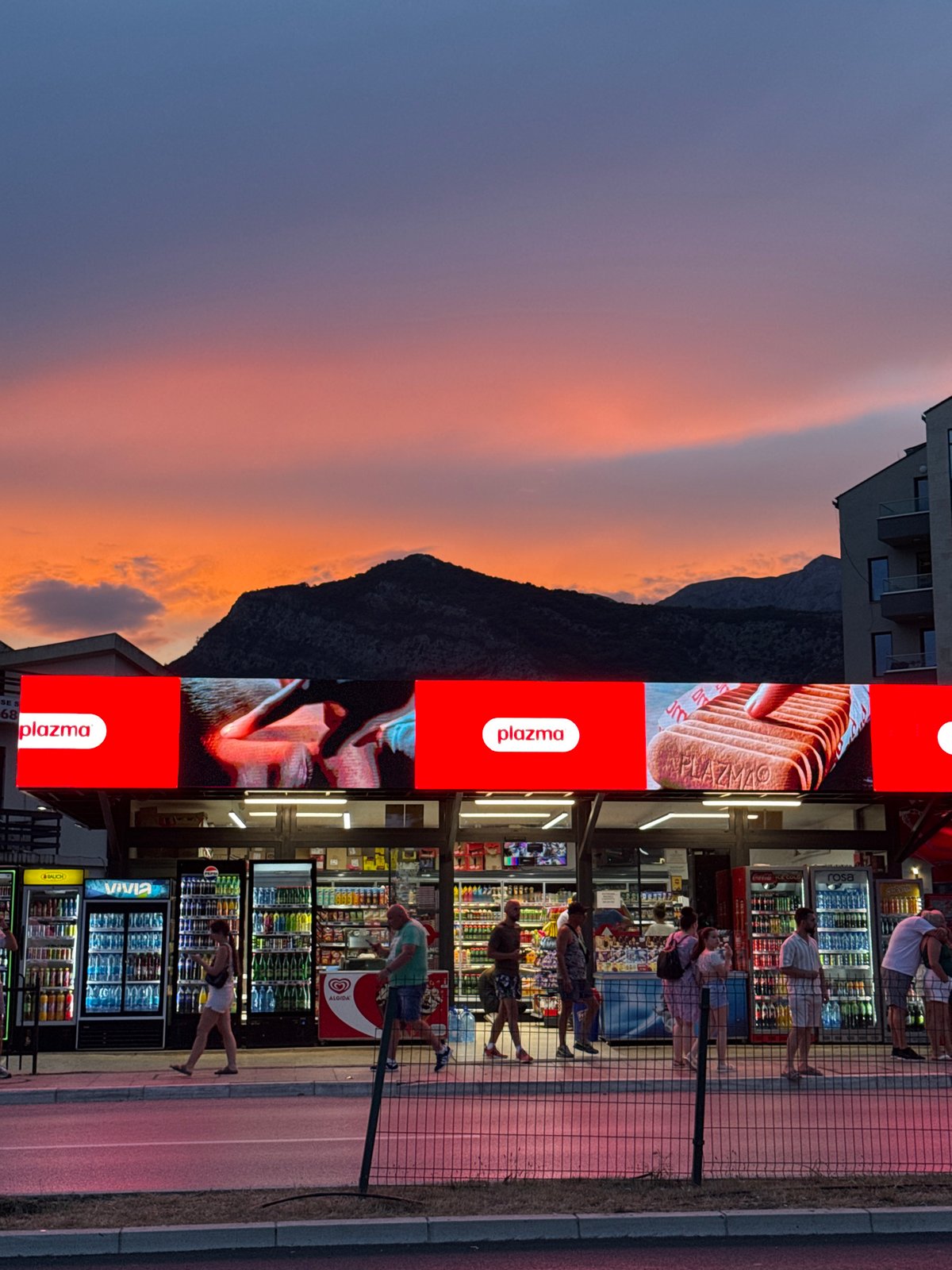 Dusk stroll past palms, storefronts, and a curved glass tower