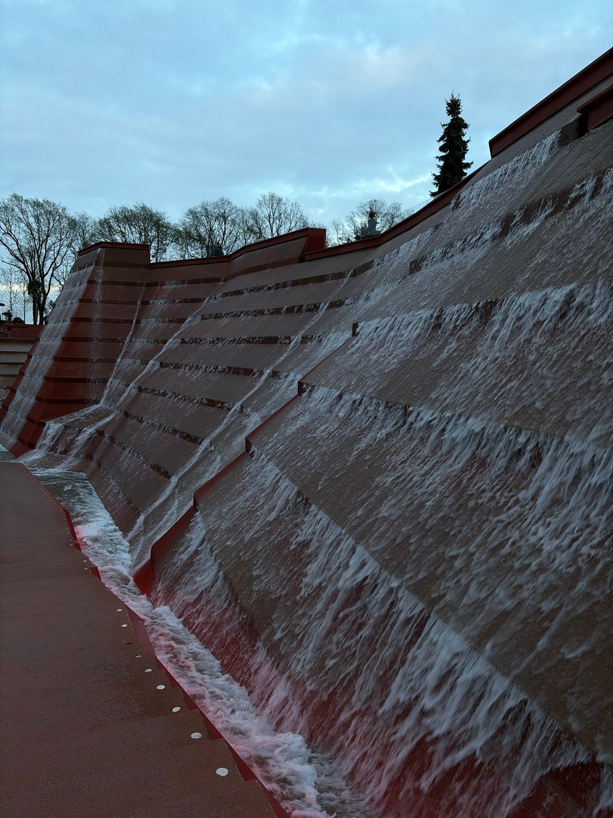 Person documents tiered waterfall feature and portraits at public space