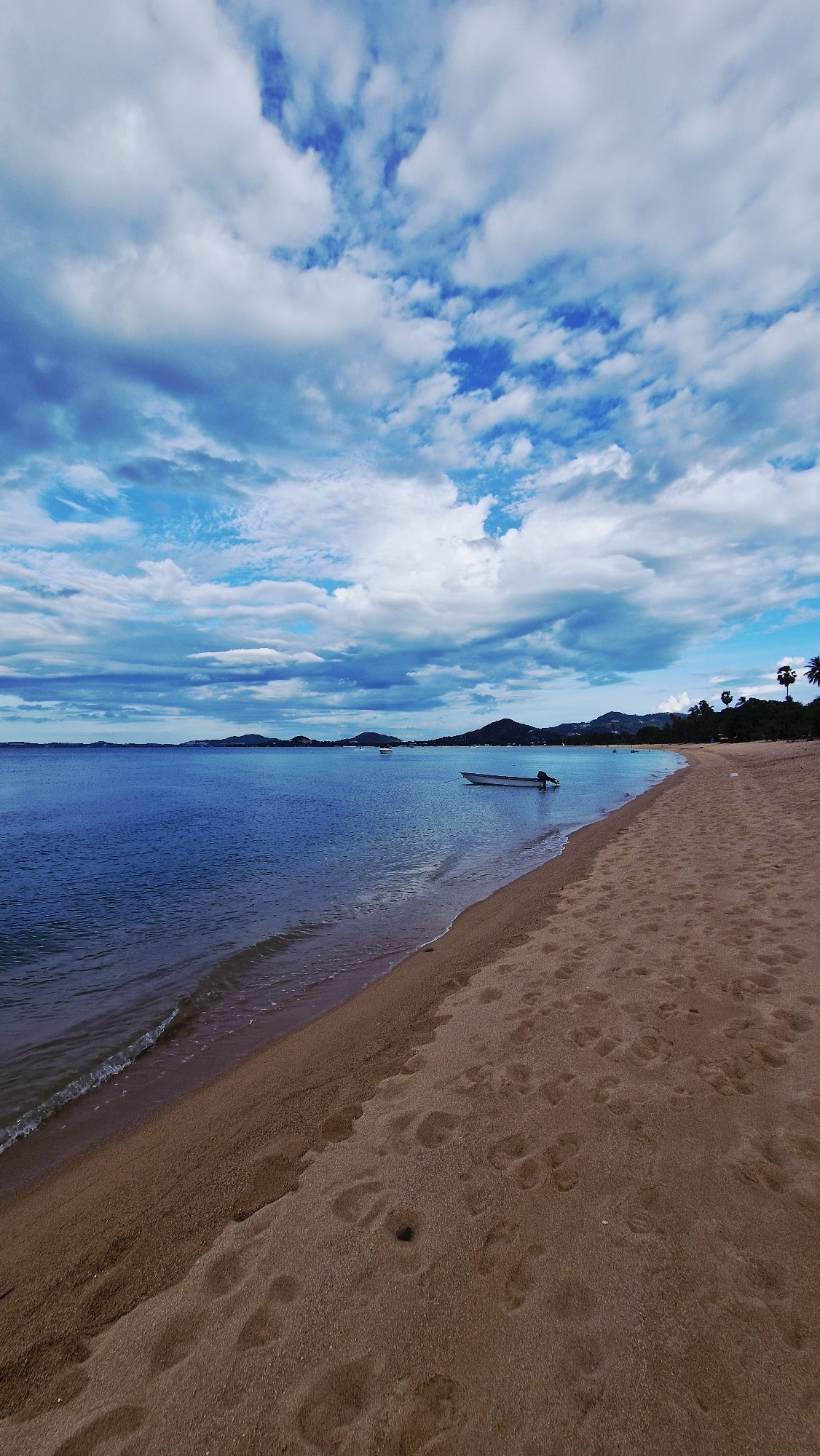 Beach scene documented in Baan Tai with footprints, waves