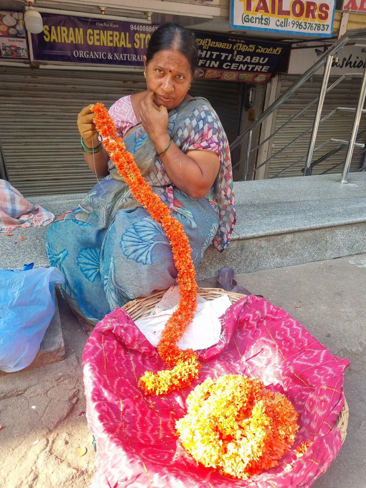 Woman creates flower garlands from marigolds in Puttaparthi