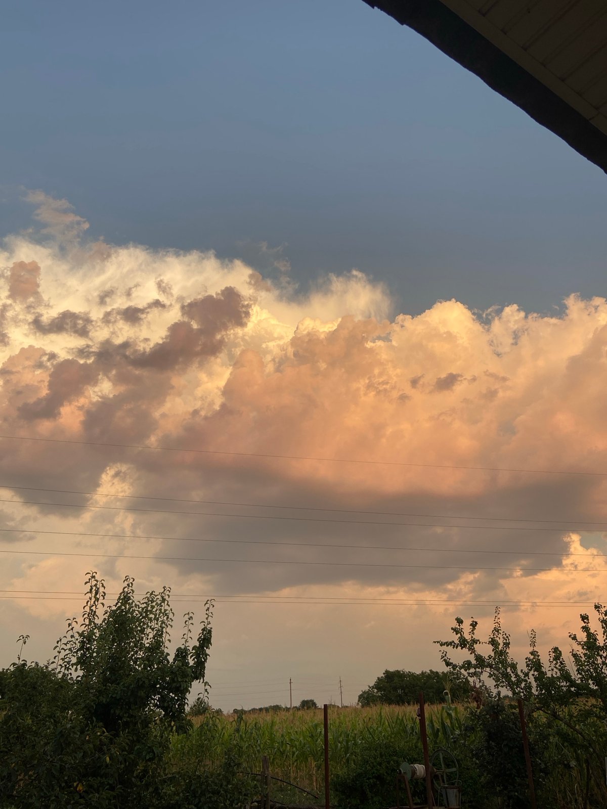 Rural sunset sky, clouds, and a parked car near a fence