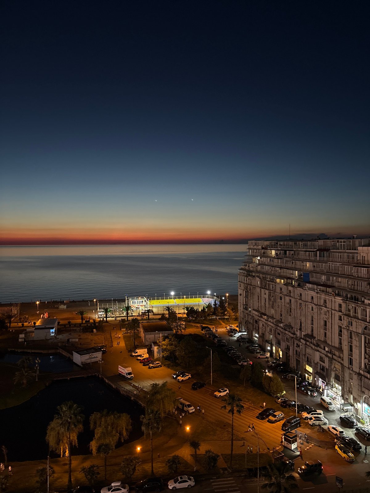 Woman documents evening scenes across modern Batumi with pet dog