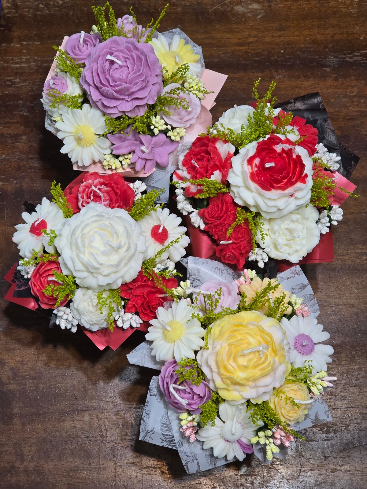 Decorative candle flower bouquets arranged on wooden surface