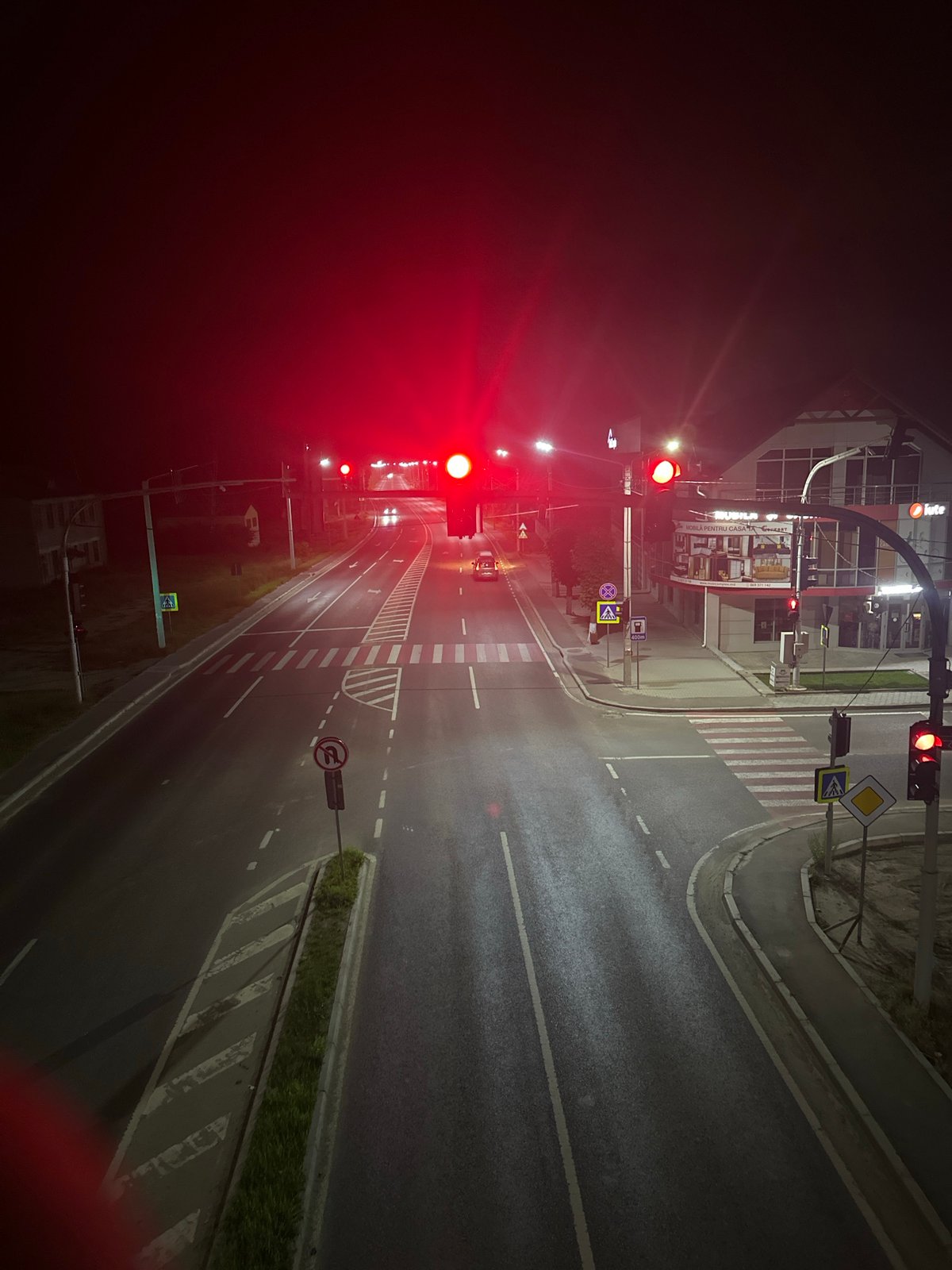 Strășeni's main street at night, storefronts to overpass