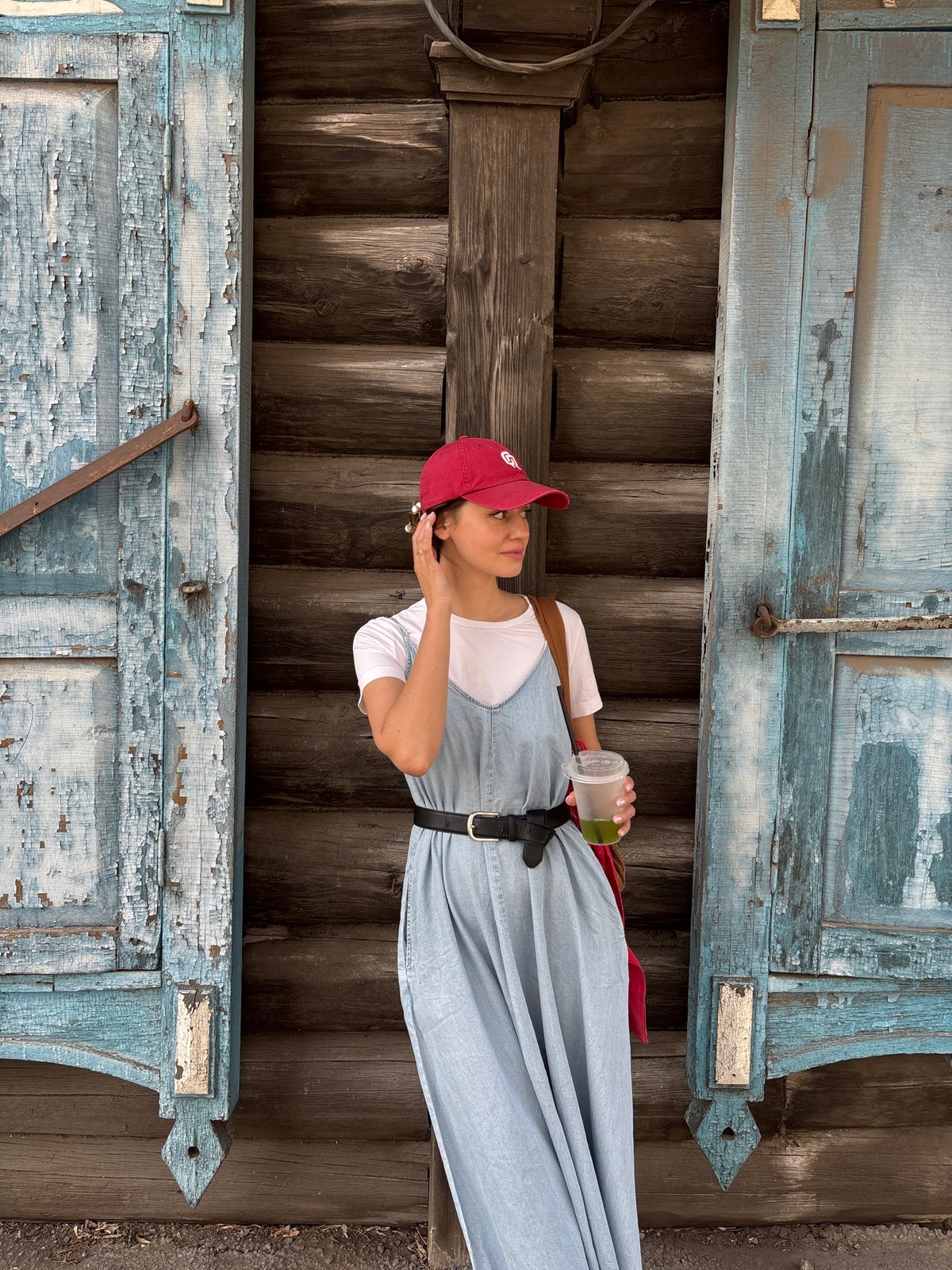 Woman in red cap photographed at wooden building in Krasnoyarsk