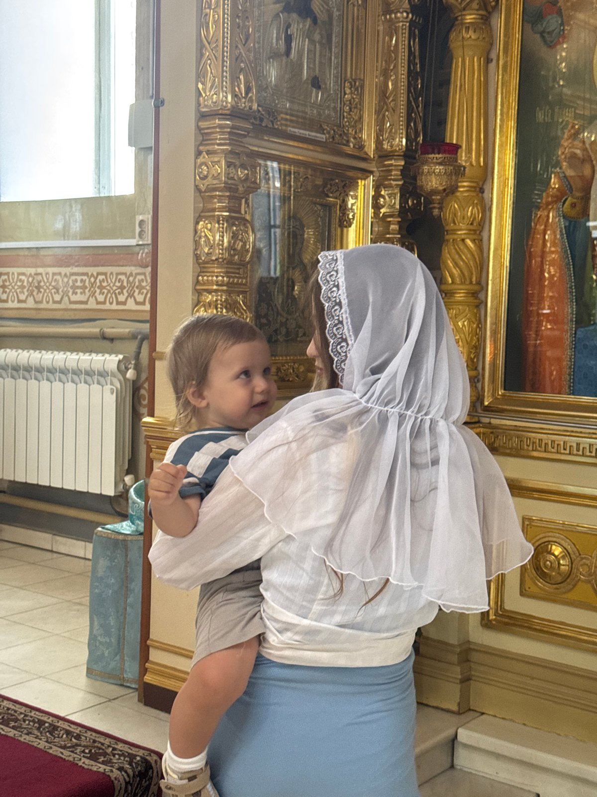 Veiled figure holds a child at a formal occasion in Tolyatti
