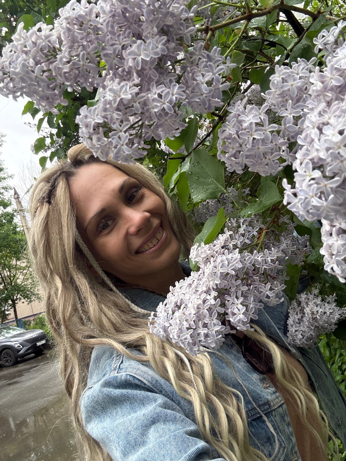 Woman poses with lilac blossoms after rain in Rusanovo